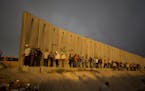 Palestinian men walk past a section of Israel's separation barrier to cross the Qalandia checkpoint on their way to pray at the Al-Aqsa Mosque in Jeru