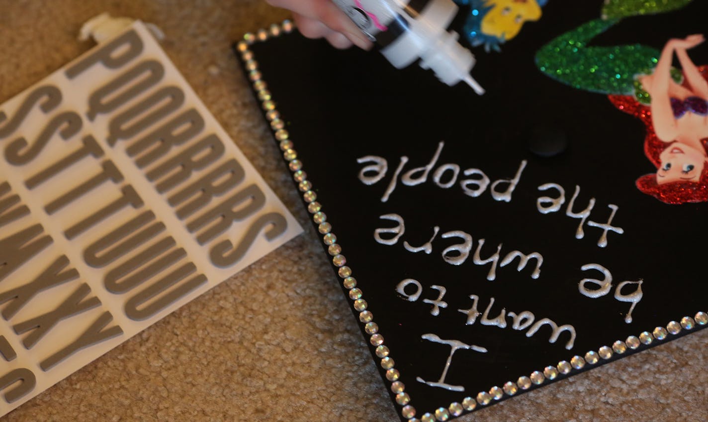 Hanna DeGroot wrote out the words on her friend Olivia Martinson's graduation cap because she had the steadier hand. ] (KYNDELL HARKNESS/STAR TRIBUNE) kyndell.harkness@startribune.com A party at Hanna DeGroot's apartment, where she and some gal pals will be decorating their graduation caps in Minneapolis Min., Friday, May 8, 2015.