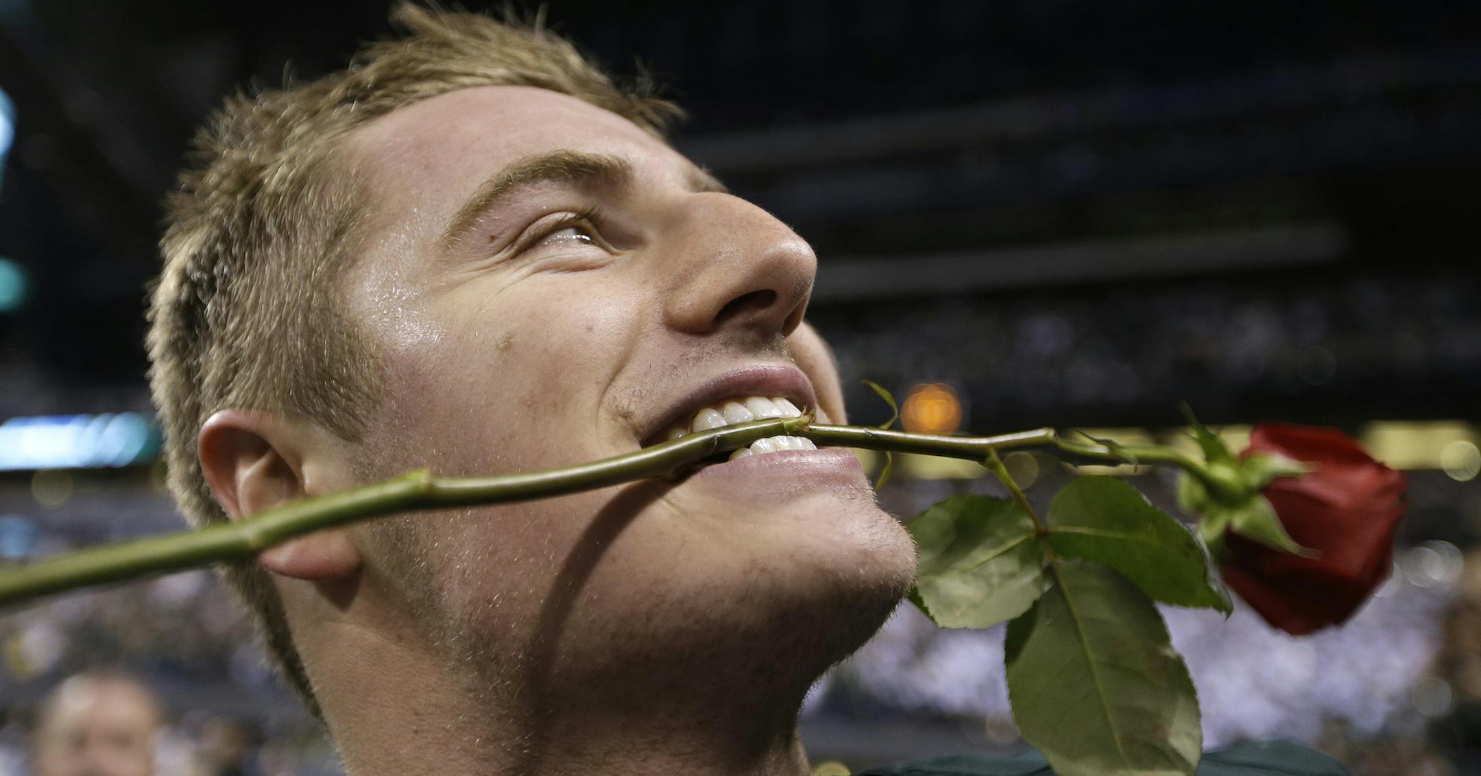 Michigan State's Connor Cook bites on a rose following the Big Ten Conference championship NCAA college football game against Ohio State early Sunday, Dec. 8, 2013, in Indianapolis. Michigan State defeated Ohio State 34-24. (AP Photo/Michael Conroy)