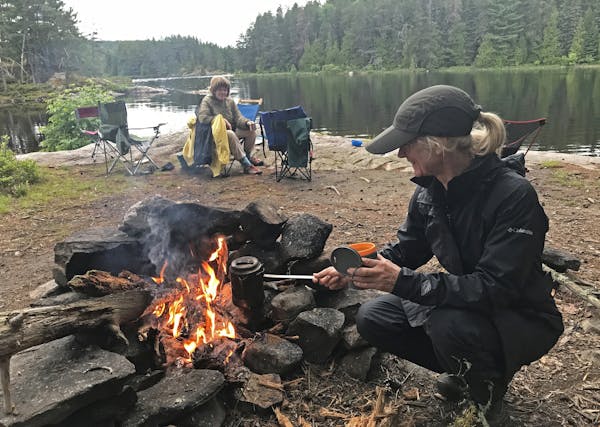 Patrice Aubrecht, foreground, prepares coffee at an island campsite in Quetico Provincial Park while Kathryn Erickson looks on. The two were part of a
