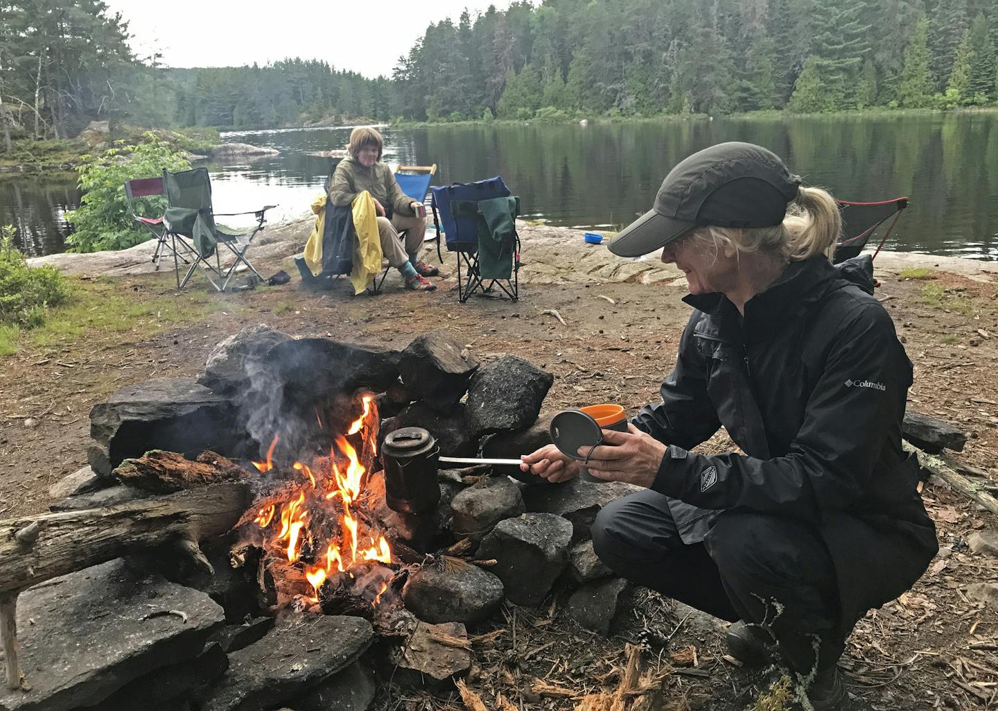 Patrice Aubrecht, foreground, prepares coffee at an island campsite in Quetico Provincial Park while Kathryn Erickson looks on. The two were part of a party of six women on the wilderness trip.