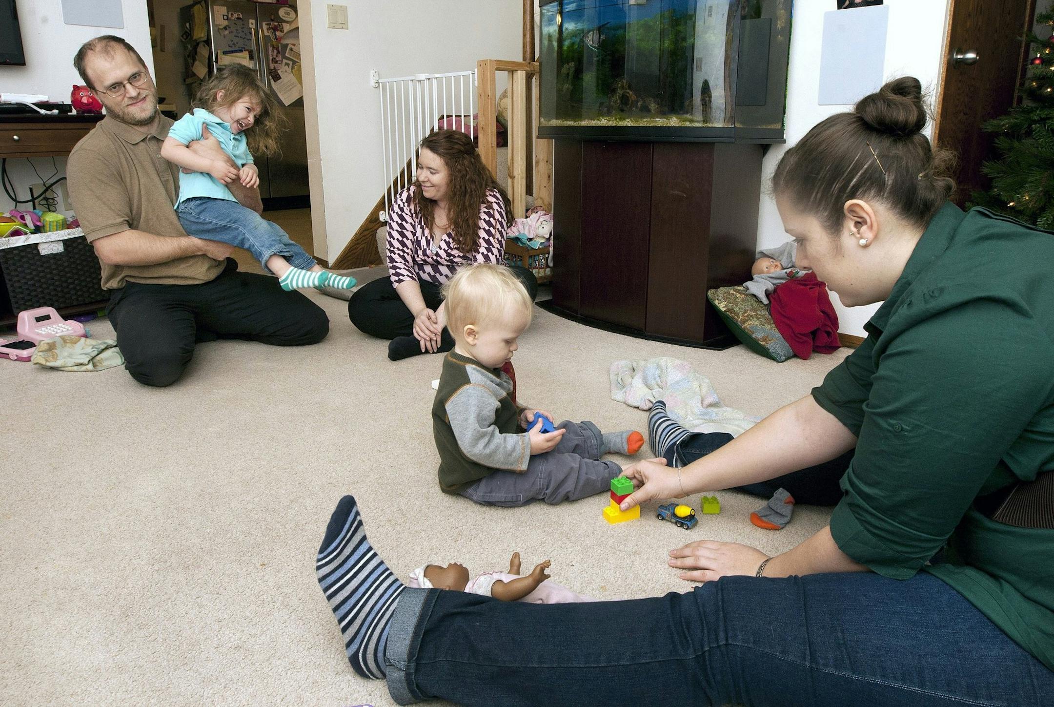 Robert and Sarah Edwards play with their daughter Ella while au pair Melanie Bargfeldt, right, plays on the floor with their son Williamat the Edwards' family home in Cummings, N.D., on Dec. 6, 2013. (John Stennes/Grand Forks Herald/MCT) ORG XMIT: 1146985