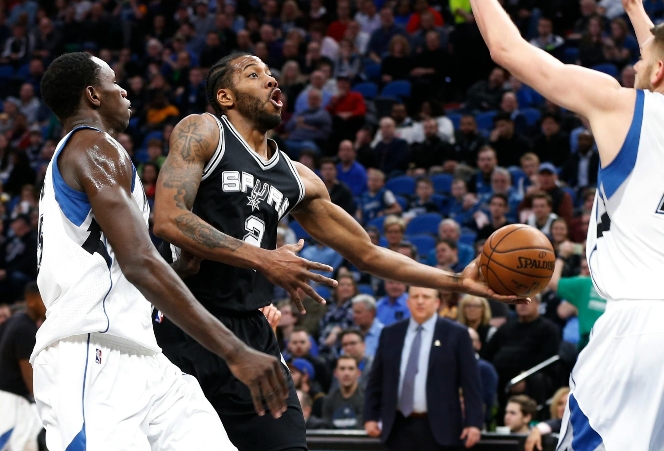 San Antonio Spurs' Kawhi Leonard, center, lays up between Minnesota Timberwolves' Gorgui Dieng, of Senegal and Cole Aldrich, right, during the first half of an NBA basketball game Tuesday, March 21, 2017, in Minneapolis. (AP Photo/Jim Mone)