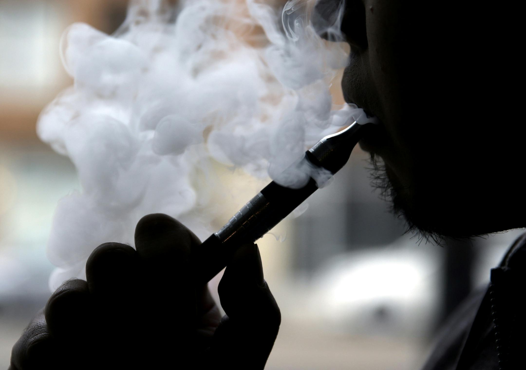 FILE - In this April 23, 2014, file photo, an electronic cigarette is demonstrated in Chicago. The Columbia/Boone County Board of Health has endorsed proposals to ban selling tobacco products to people younger than 21. The Columbia Tribune reports the board also approved on Thursday a proposal to add e-cigarettes to Columbia's restrictions on smoking inside public places. (AP Photo/Nam Y. Huh, File) ORG XMIT: MIN2014120511365831