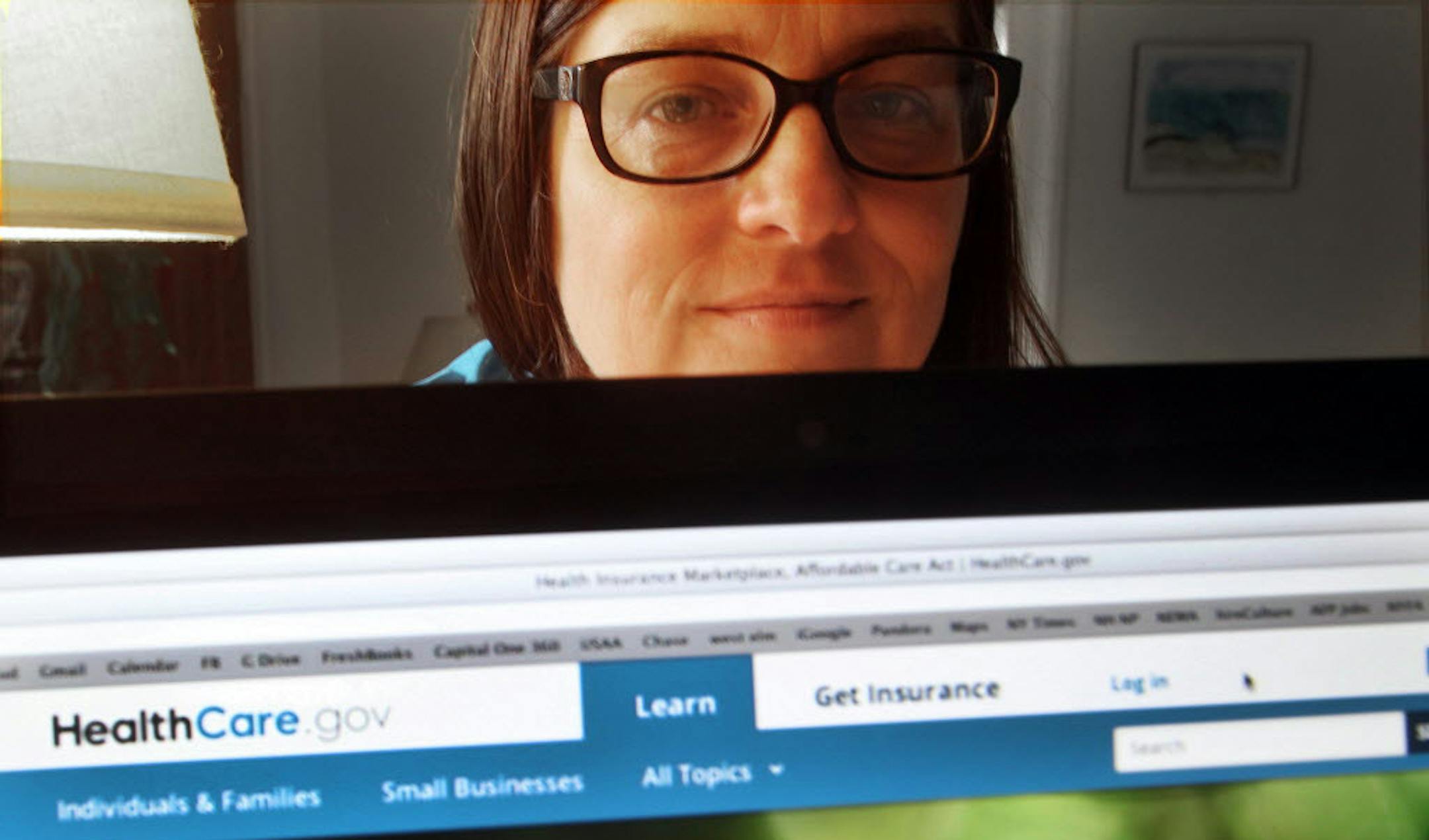 Deborah Lielasus poses behind her computer with the national health insurance enrollment website.