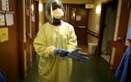 Registered nurse Syndie Pascal dons personal protective equipment before checking a COVID-19 patient on the fifth floor ICU at Bethesda Hospital in St