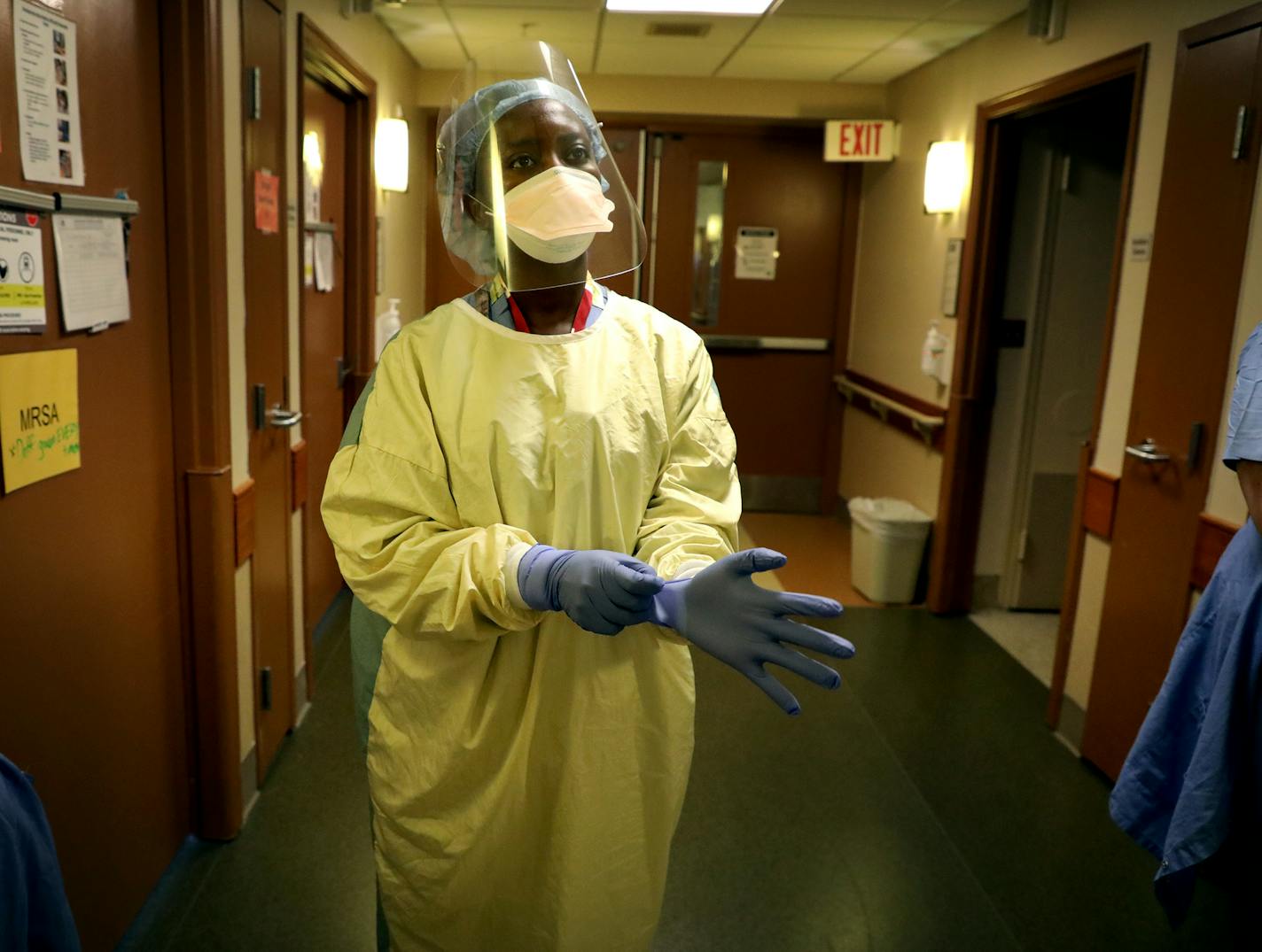 Registered nurse Syndie Pascal dons personal protective equipment before checking a COVID-19 patient on the fifth floor ICU at Bethesda Hospital in St. Paul.