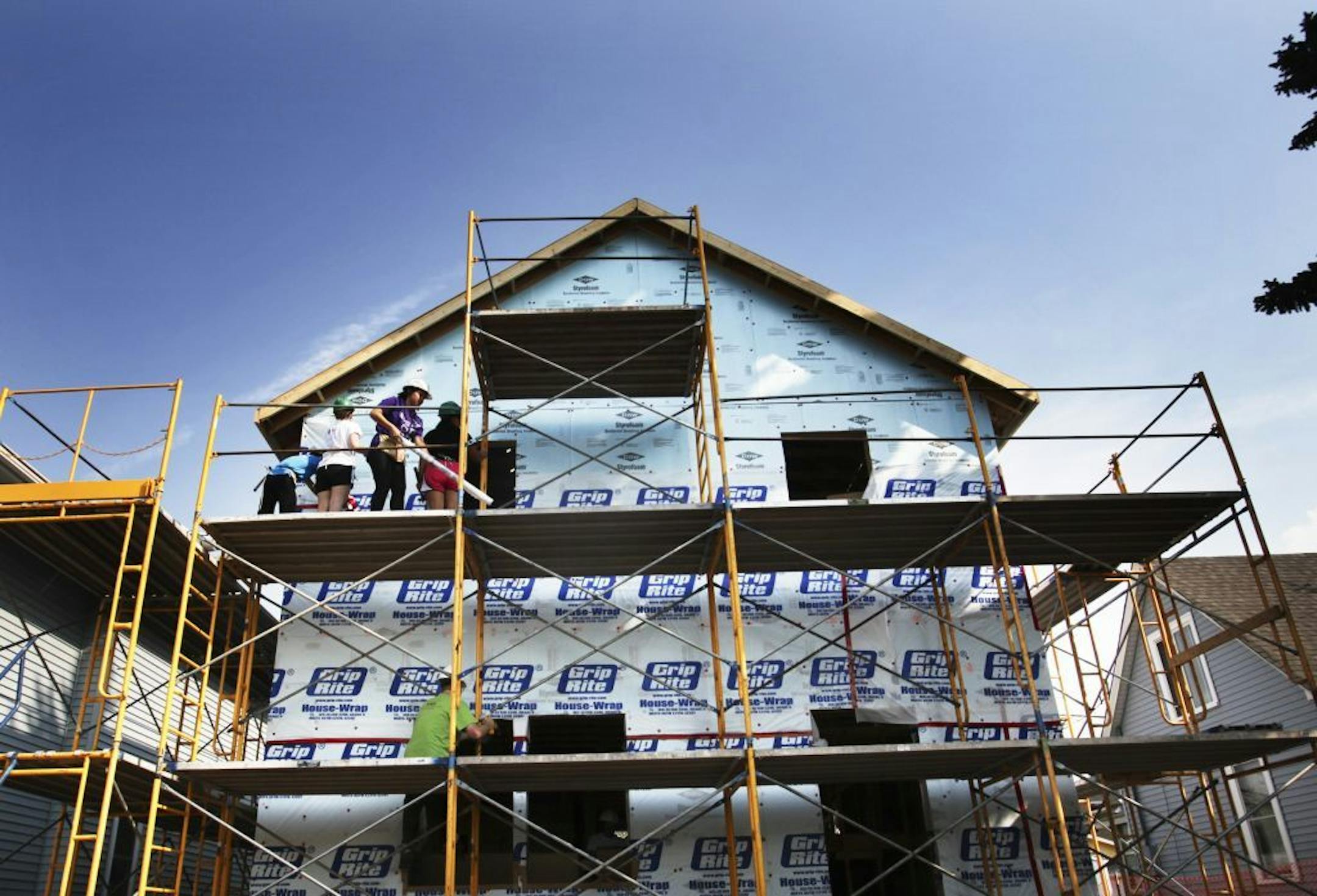 High School students and other volunteers work on the exterior of the four bedroom home that when finished will house a family of seven Thursday, Aug. 30, 2012, in St. Paul, MN.
