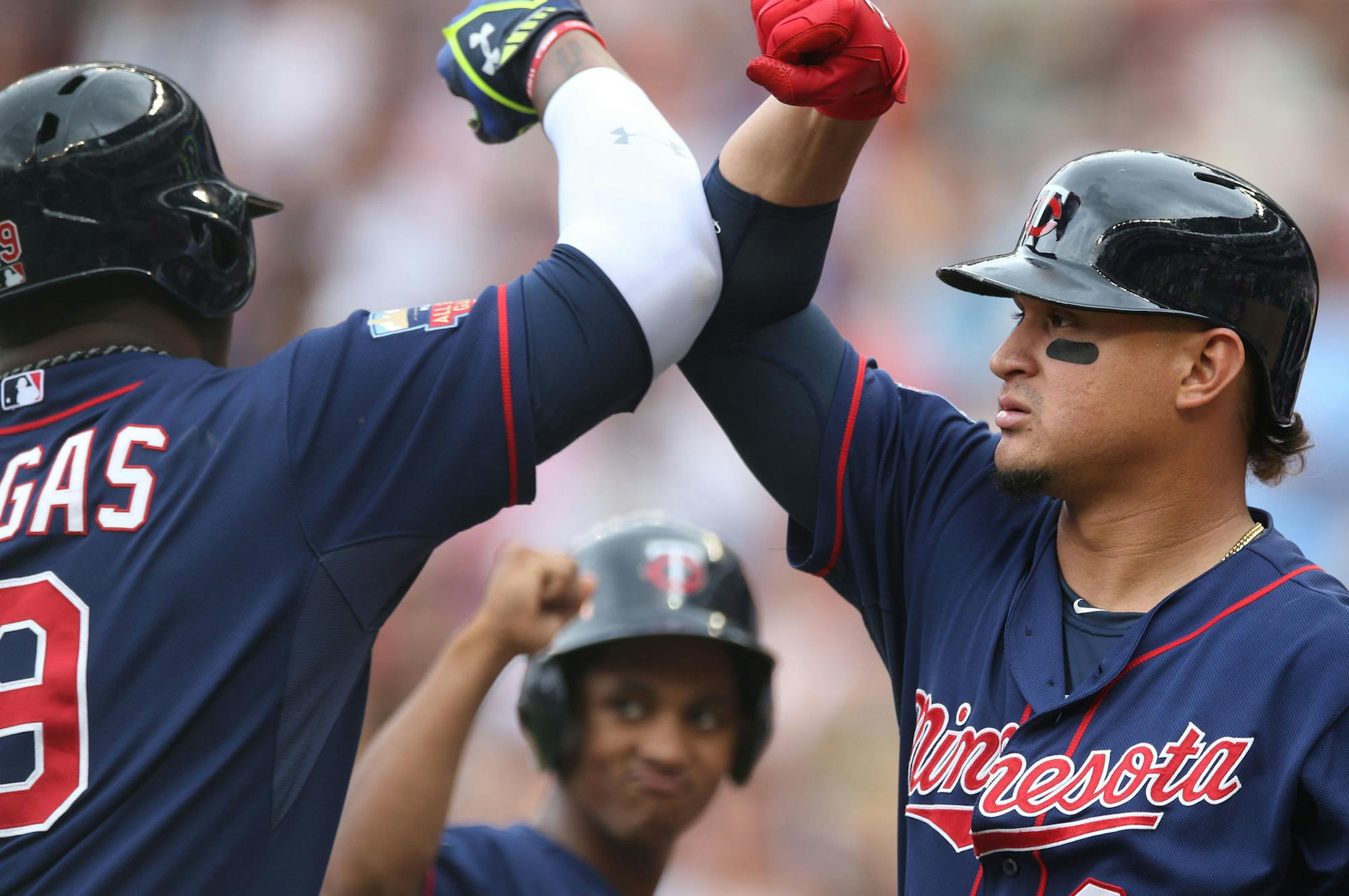 Minnesota Twins' Oswaldo Arcia, right, gives an elbow bump to Kennys Vargas as a ball boy, center, waits his turn after Vargas hit a solo home run off Cleveland Indians pitcher Corey Kluber in the fourth inning of a baseball game, Thursday, Aug. 21, 2014, in Minneapolis. (AP Photo/Jim Mone)