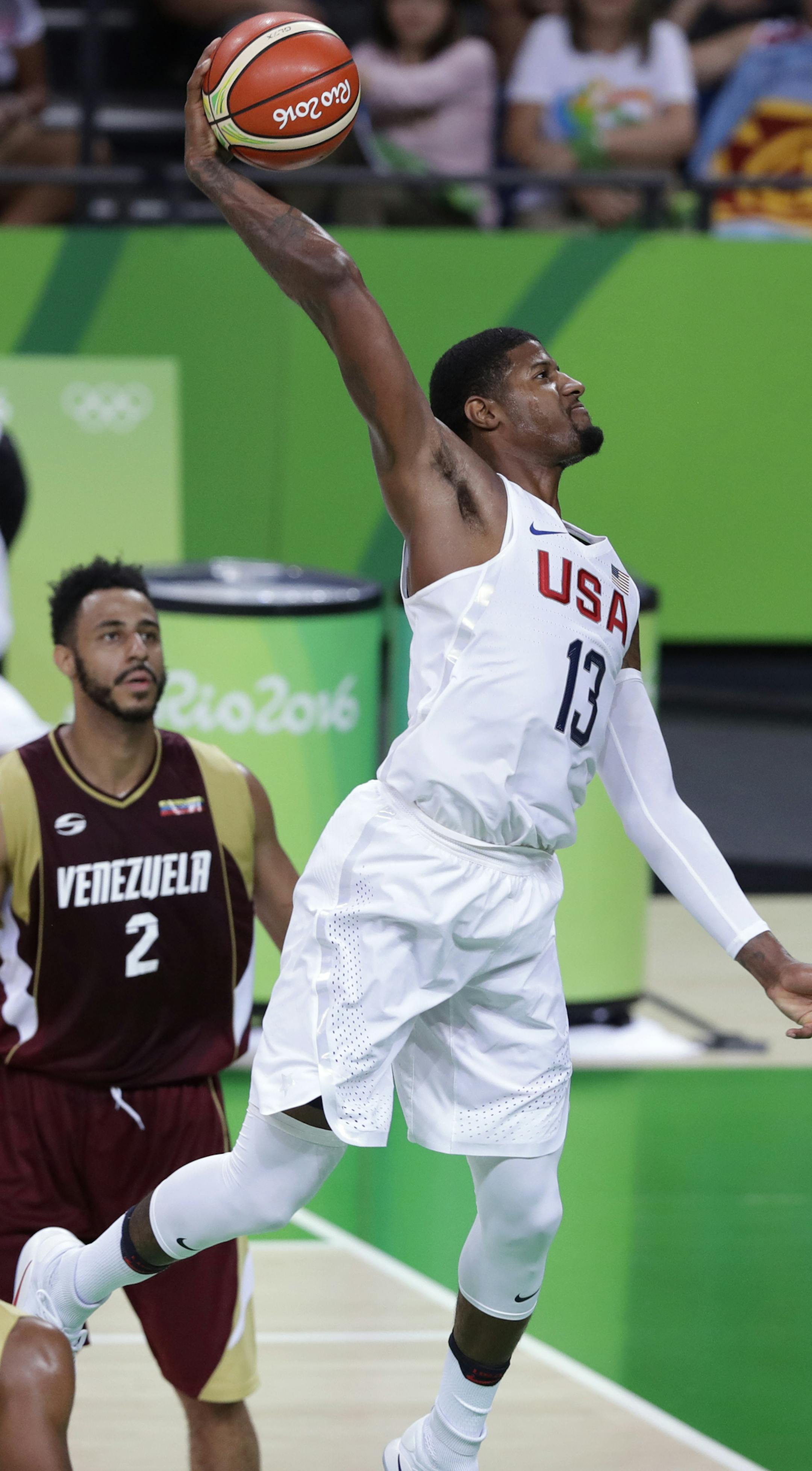 United States' Paul George (13) dunks the ball over Venezuela's Dwight Lewis, left, during a basketball game at the 2016 Summer Olympics in Rio de Janeiro, Brazil, Monday, Aug. 8, 2016. (AP Photo/Charlie Neibergall) ORG XMIT: OBKO132