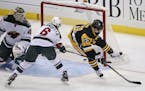 Pittsburgh Penguins' David Perron (57) gets the puck behind Minnesota Wild goalie Devan Dubnyk (40) with Marco Scandella (6) defending in the first pe