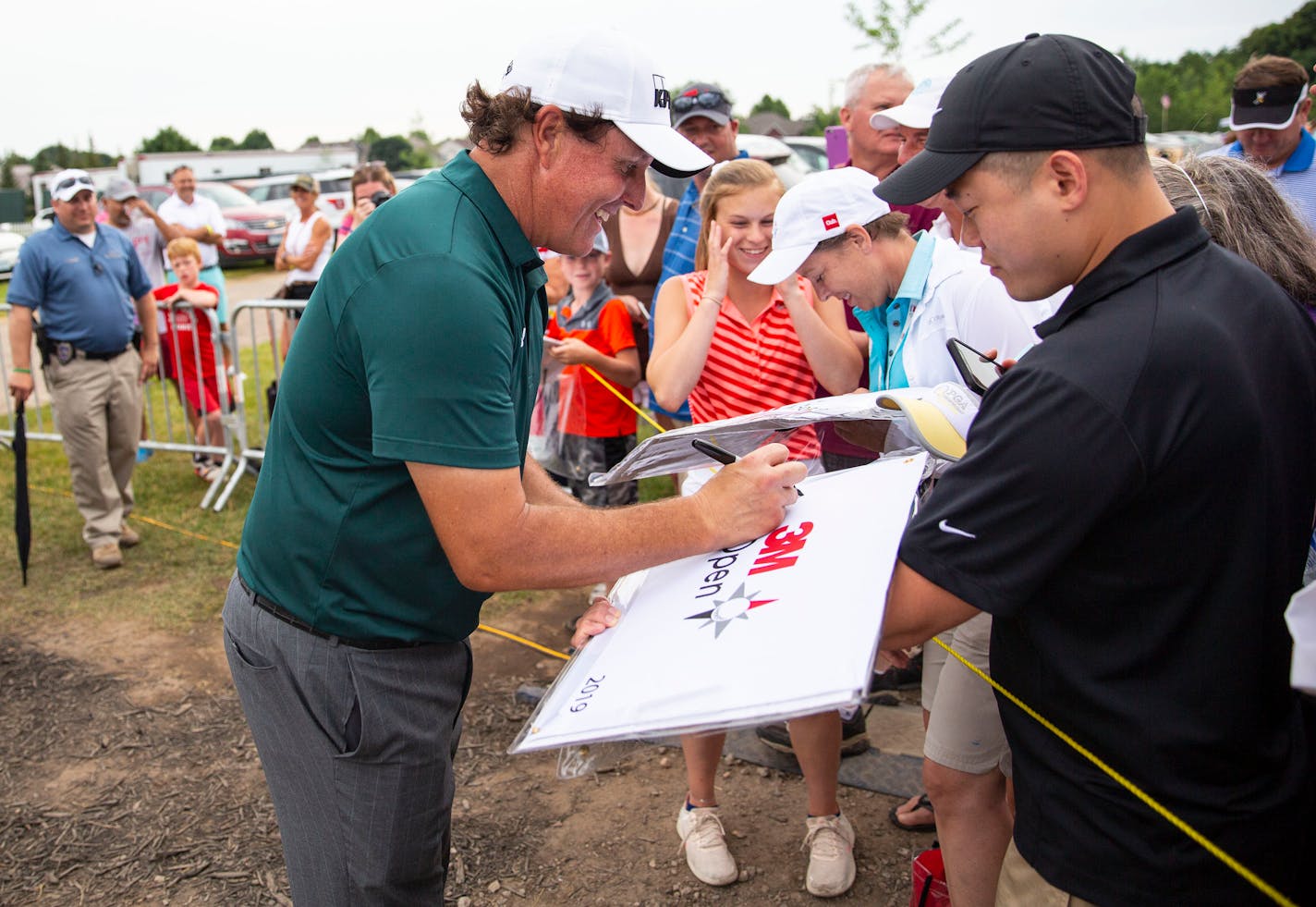 Phil Mickelson signs autographs for fans lined up near the eighteenth hole.