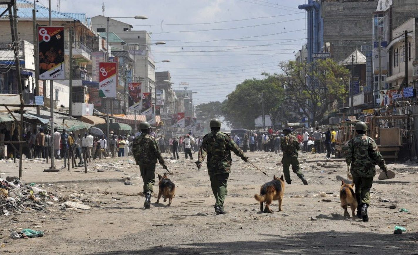 FILE - In this Nov. 19, 2012 file photo, Kenyan police with dogs patrol a street in Eastleigh to prevent two groups from clashing.