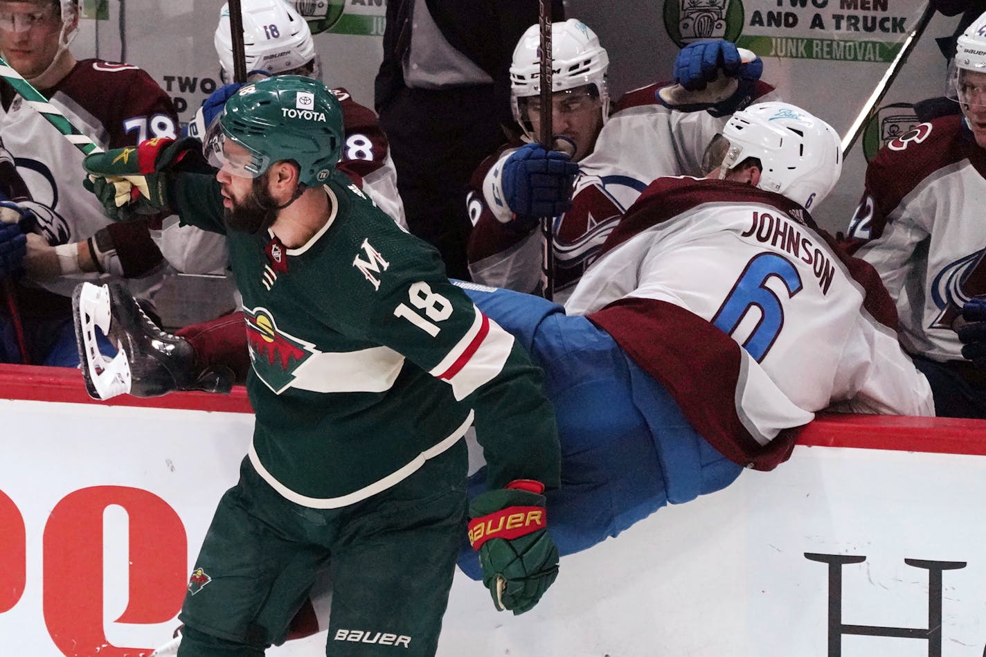 Minnesota Wild's Jordan Greenway (18) checks Colorado Avalanche's Erik Johnson (6 ) into the Wild bench in the second period of an NHL hockey game Friday, April 29, 2022, in St. Paul, Minn. (AP Photo/Jim Mone)