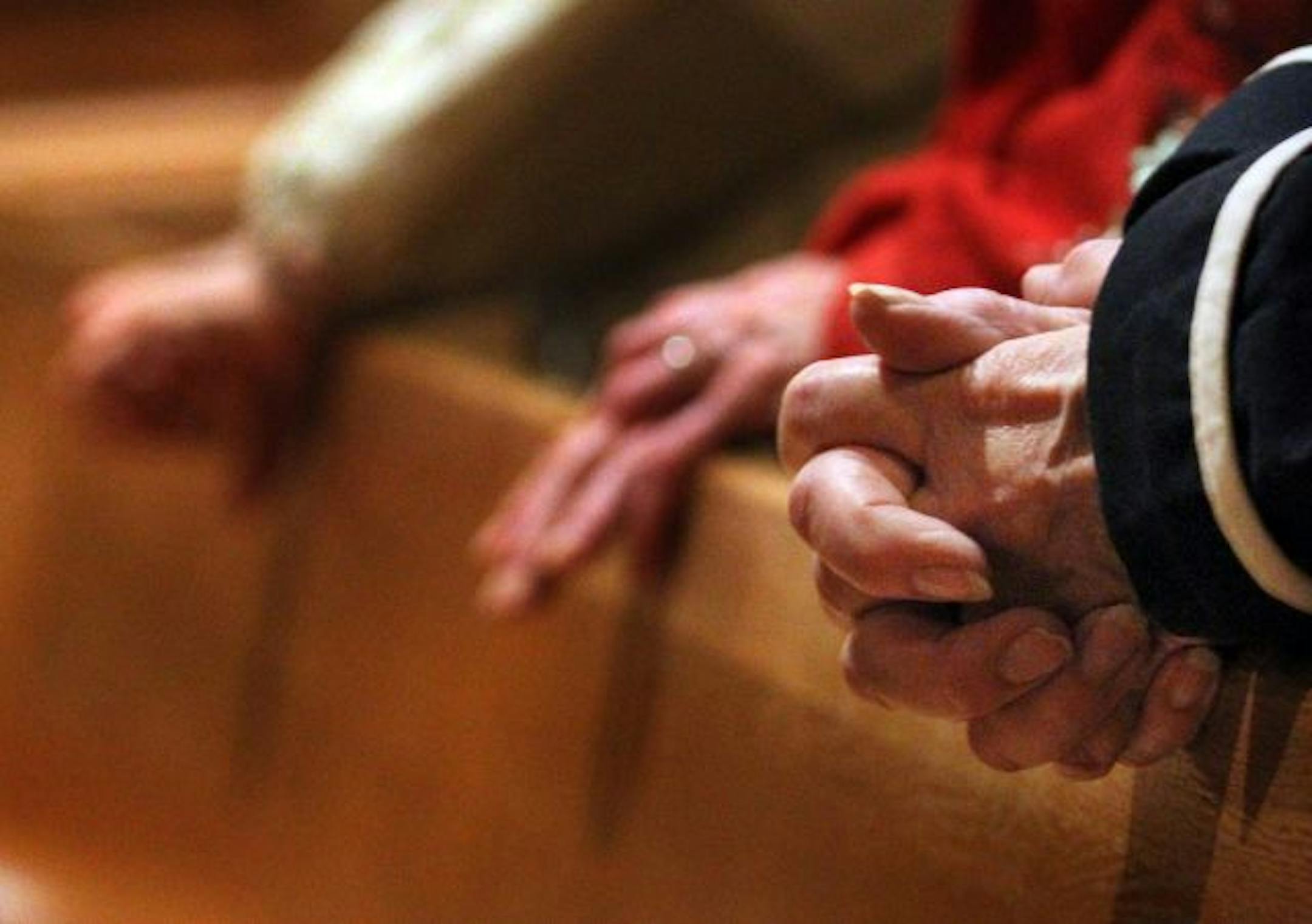 St. Austin Catholic Church is one of the 21 churches slated to merge with another parish under the Archdiocese of St. Paul/Minneapolis plan to reorganize. However, they're planning to appeal that plan, along with a handful of other churches. In this photo:] Parishoner Rosemary McGuigan, right, folds her hands in prayer during morning mass. Of the proposed mergers, McGuigan said: "It will disrupt our whole community."
