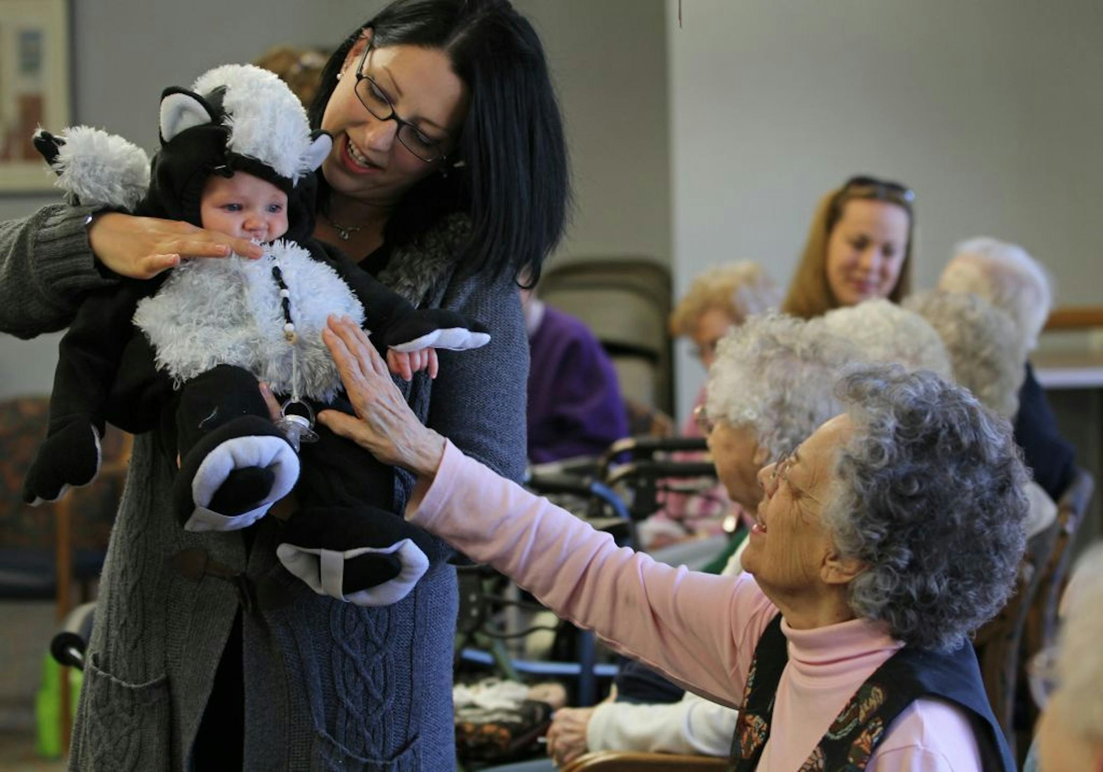 Dante Zeien was held by his mother, Micola Zeien, as Oak Meadows Senior Center resident Marynetta Hartung reached out during a senior/kids Halloween party sponsored by the MOMS of Woodbury group. The party took place in the community room of the senior center.