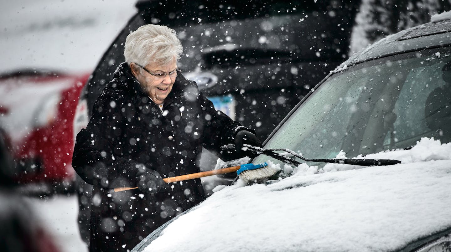 Nancy Dickinson of Apple Valley brushed the new wet snow from her car In Eagan as Minnesotans braved another barrage of snow Thursday, February 20, 2014. ] GLEN STUBBE * gstubbe@startribune.com