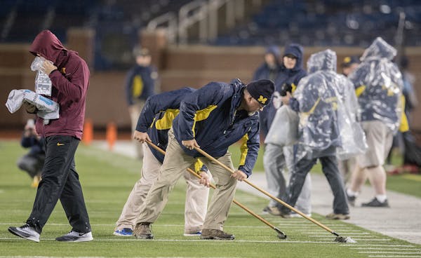 Michigan field crew clear areas of flooding after a weather delay before the Gophers took on Michigan in Michigan Stadium, Saturday, November 4, 2017 