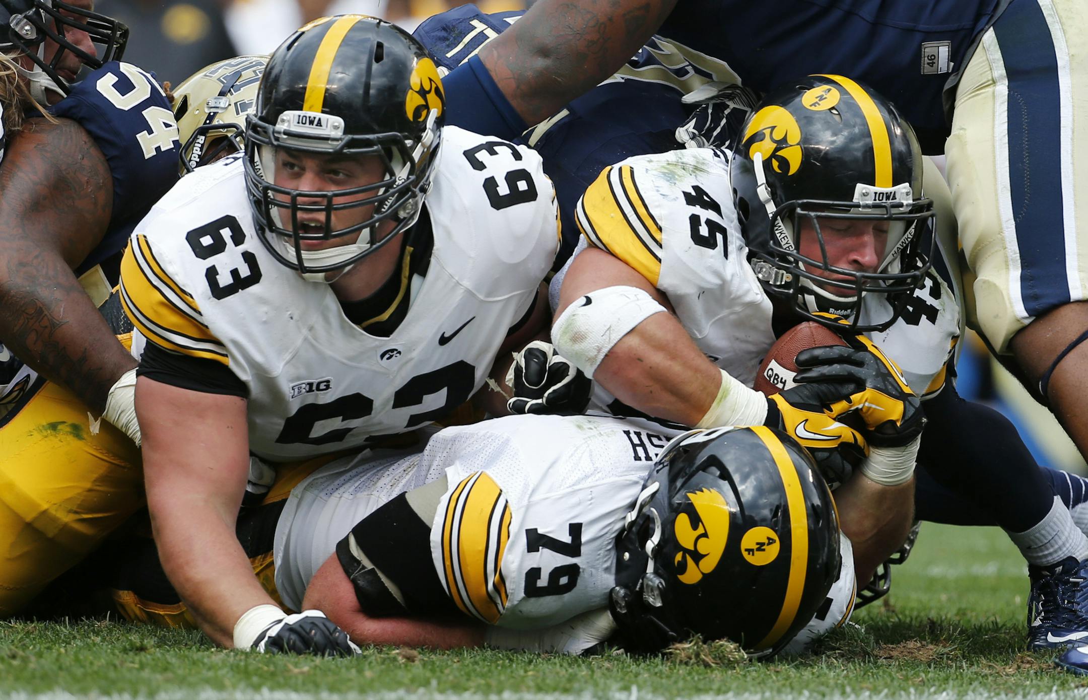 Iowa running back Mark Weisman (45) is sandwiched between Iowa offensive linesman Sean Welsh (79) and Iowa offensive linesman Austin Blythe (63) as they come up short of the goal line late in the fourth quarter of an NCAA college football game against Pittsburgh in Pittsburgh, Saturday, Sept. 20, 2014. Weisman scored on the next play and Iowa won 24-20. (AP Photo/Gene Puskar)