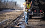 St. Paul street workers smoothed asphalt over a pothole on Shepard Road. In some cases, Minnesota motorists can be reimbursed for repairs if their car