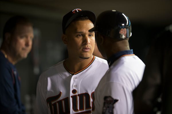 Minnesota Twins left fielder Oswaldo Arcia chats with first base coach Butch Davis in the dugout between innings during Wednesday night's game against