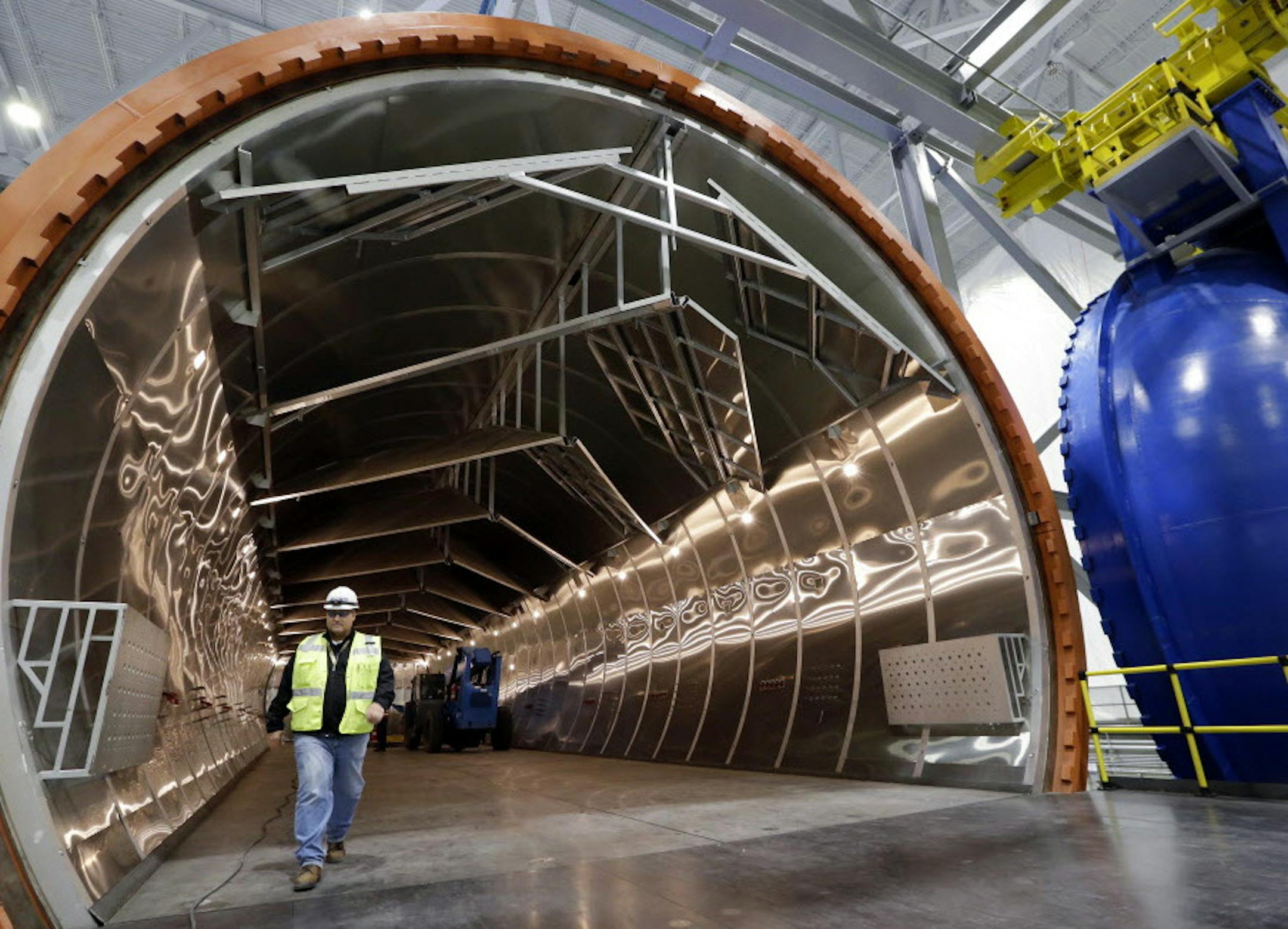 A worker walks out of a massive autoclave that will be used to bake carbon fiber wings with super-heated pressure, during a tour of the new Boeing 777X Composite Wing Center a day ahead of its grand opening, Thursday, May 19, 2016, in Everett, Wash. The facility, which is still under construction, will manufacture the world's largest composite wings for Boeing's newest commercial jetliner, the 777X. The new $1 billion, 1 million square foot center is close to the widebody plant where the 777X wi