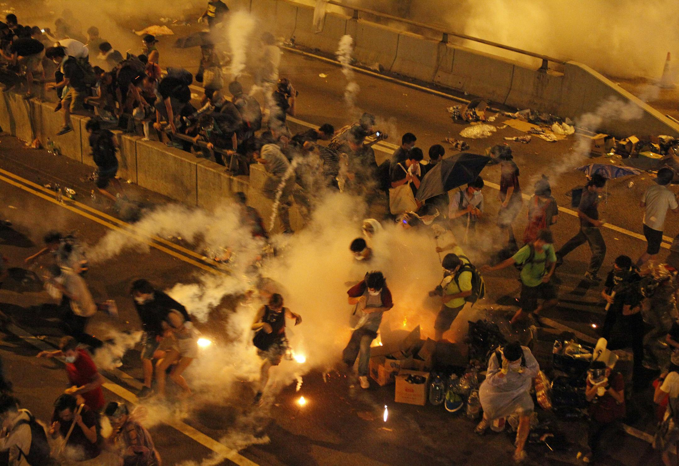 Riot police use tear gas against protesters after thousands of people blocked a main road at the financial central district in Hong Kong, Sunday, Sept. 28, 2014. Hong Kong police used tear gas on Sunday and warned of further measures as they tried to clear thousands of pro-democracy protesters gathered outside government headquarters in a challenge to Beijing over its decision to restrict democratic reforms for the city. (AP Photo) HONG KONG OUT