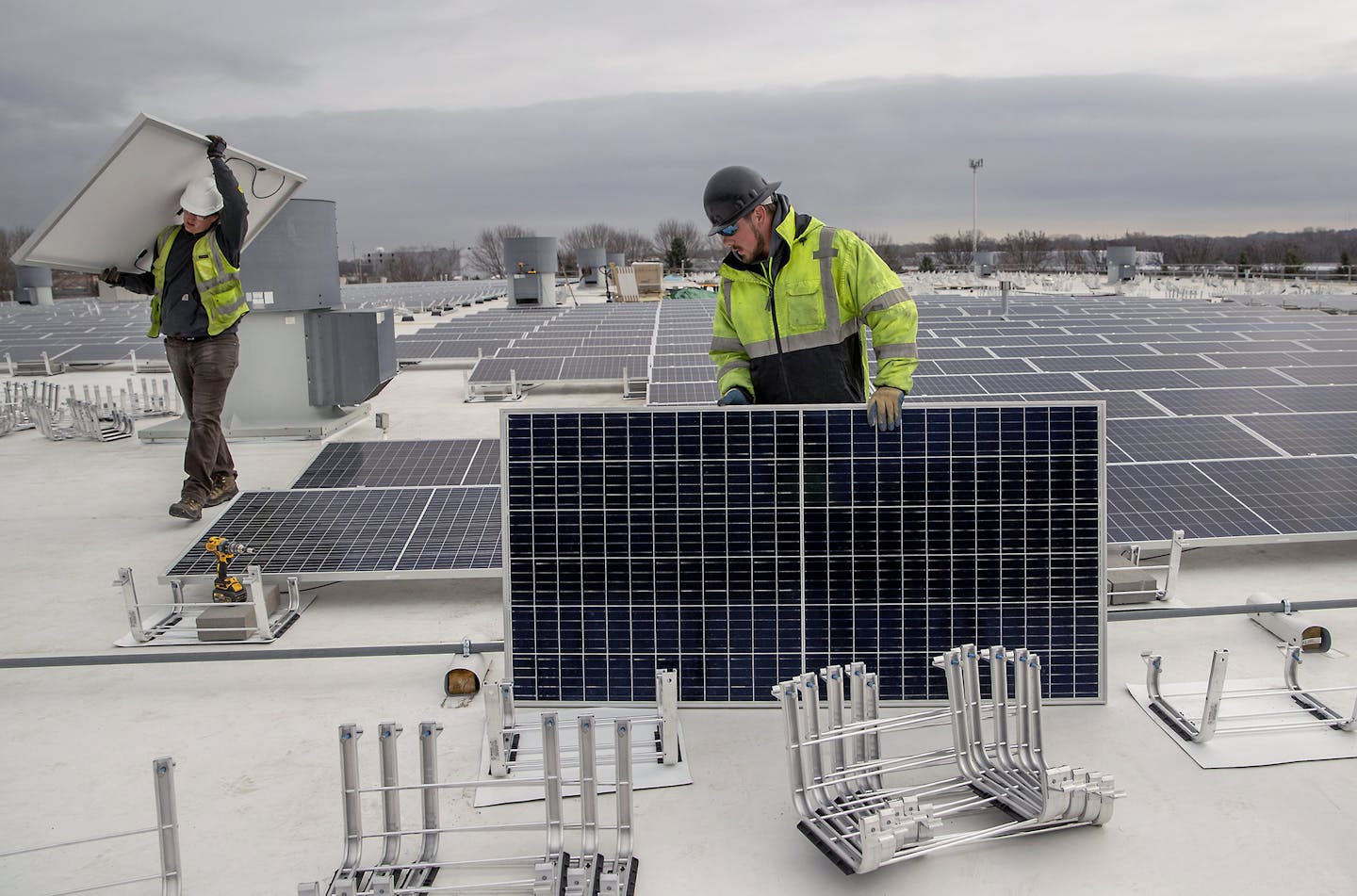 Cedar Creek Energy workers, including Rob Woodward, left, and Matt Otzelberger, installed solar panels on the roof of Brin Glass, on Monday April 6, in Fridley.