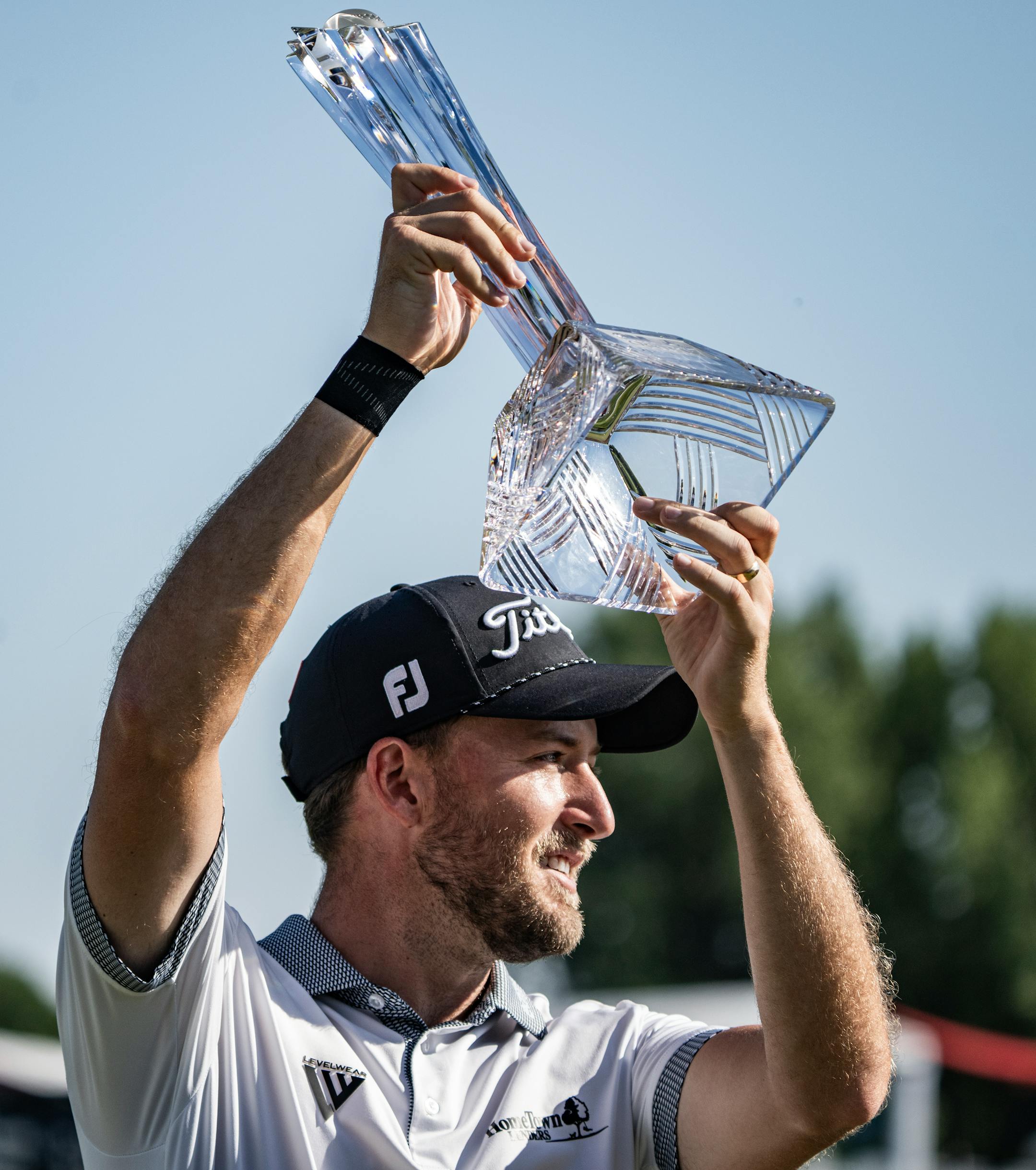 Lee Hodges hoists the 3M Open trophy after his wire-to-wire win.