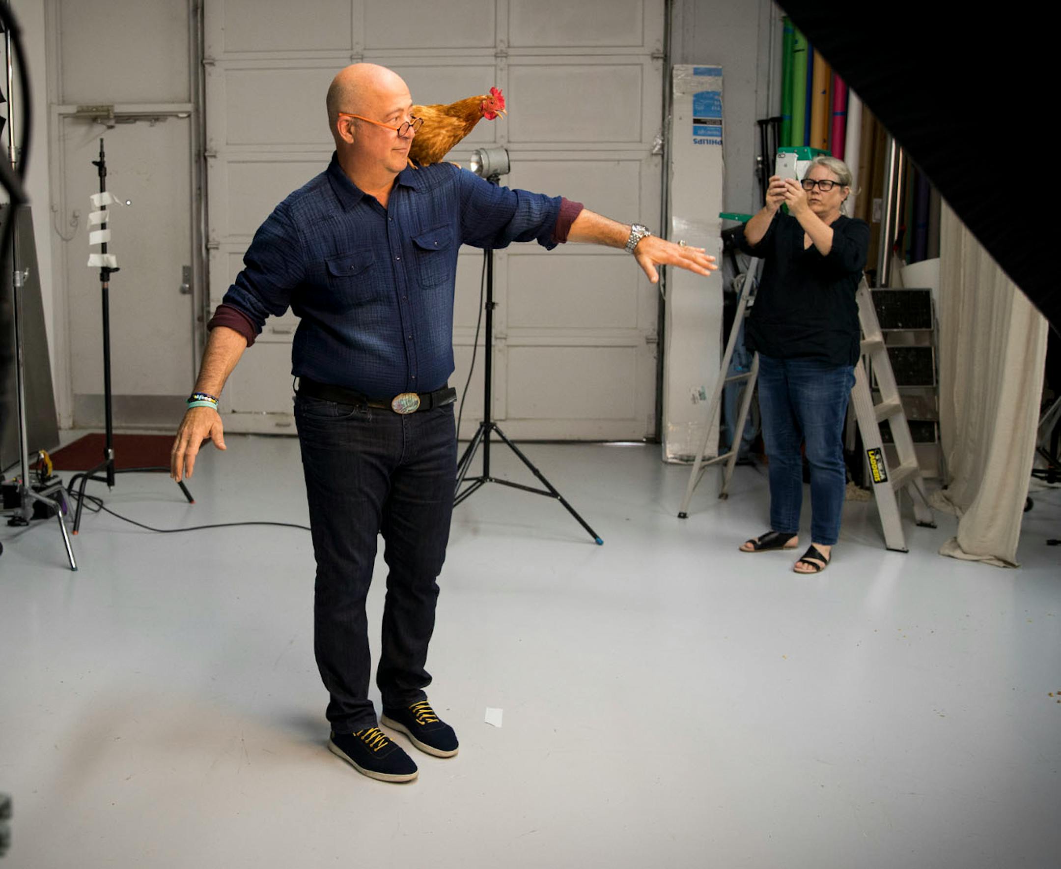 Andrew Zimmern posed with a hen as the hen's owner Mary Jo Hoffman took a picture with her phone during a photoshoot for a Midwest Living story at photographer Steve Henke's studio in Golden Valley, Minn., on Friday, May 26, 2017.