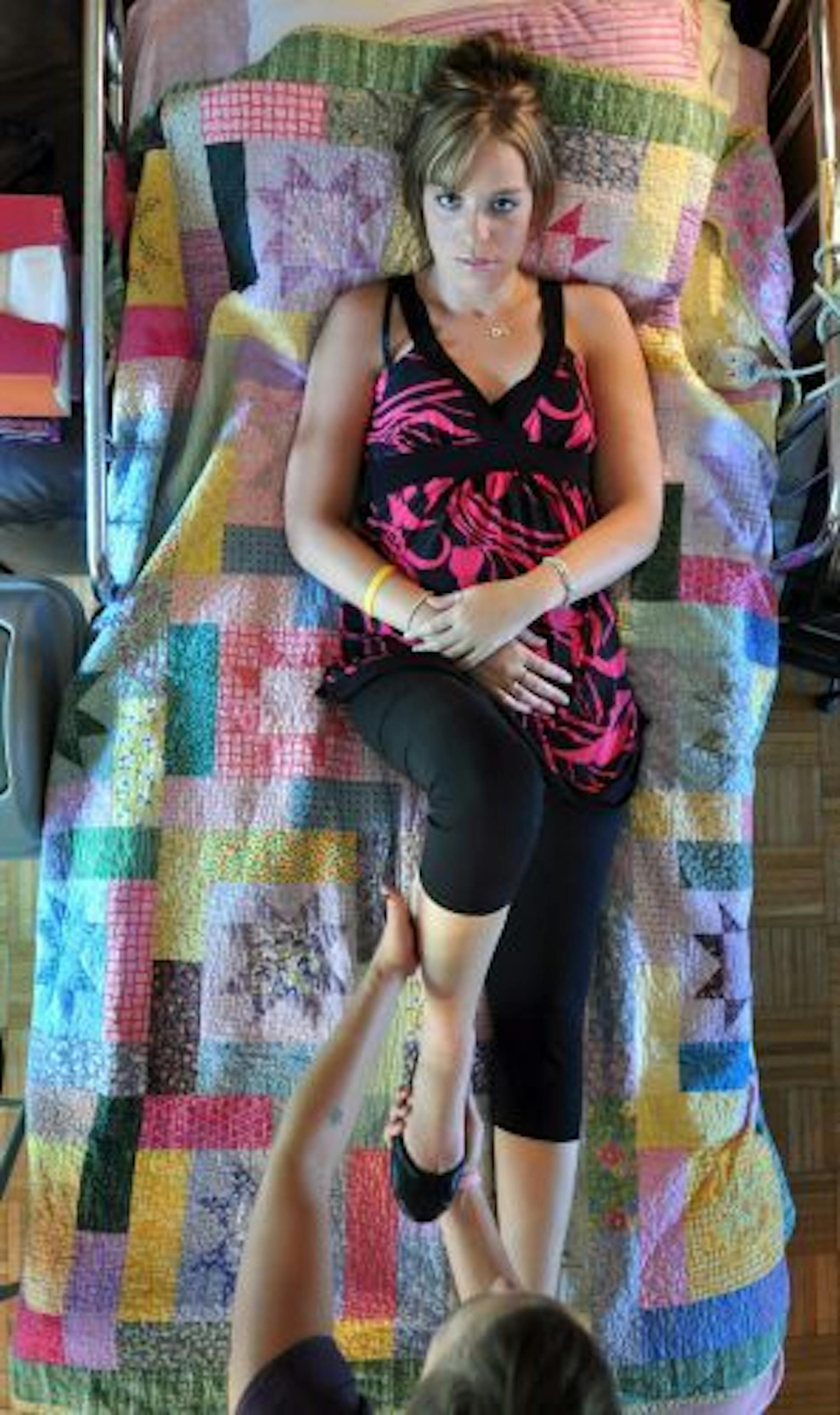 Stephanie Smith lies in her bed as her personal care assistant and best friend Emily Brutger helps move her legs at her home in Cold Spring, Minn., on Aug. 11, 2009.