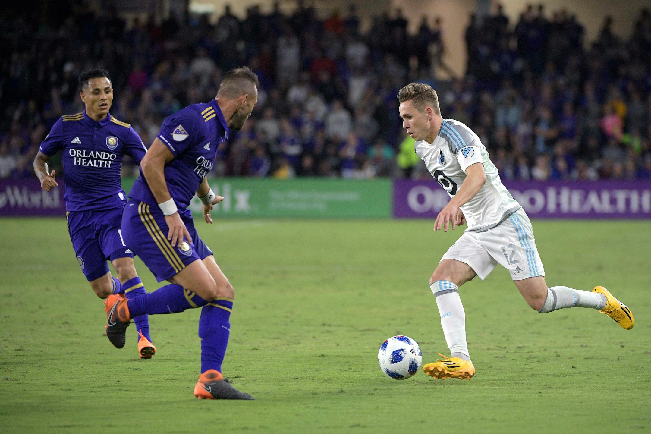 Minnesota United midfielder Sam Nicholson (12) pushes the ball in front of Orlando City defender Yoshimar Yotun (19), left, and midfielder Scott Sutter during the first half of an MLS soccer match Saturday, March 10, 2018, in Orlando, Fla. Minnesota won 2-1. (Phelan M. Ebenhack for the Star-Tribune) ORG XMIT: OTKMINN119