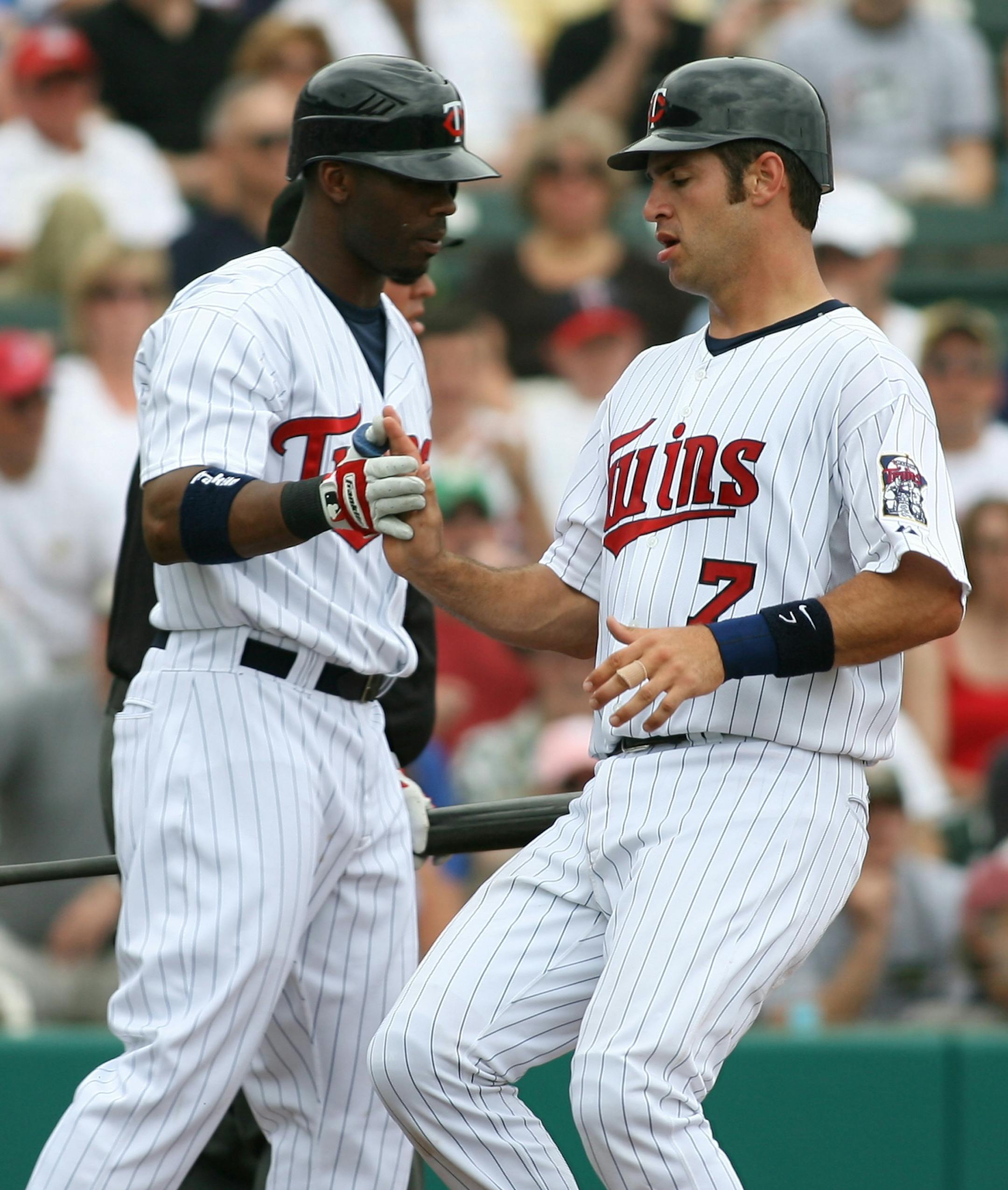 Minnesota Twins' Joe Mauer, right, is greeted by teammate Craig Monroe, left, after scoring a run on an RBI single by teammate Justin Morneau during the third inning of a spring training baseball game against the Pittsburgh Pirates Friday in Fort Myers, Fla.