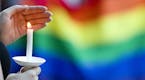 A candle burns in front of a pride flag while community members gather for a vigil to honor the victims of the attack on a nightclub in Orlando, Fla. 