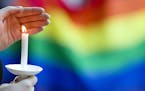 A candle burns in front of a pride flag while community members gather for a vigil to honor the victims of the attack on a nightclub in Orlando, Fla. 
