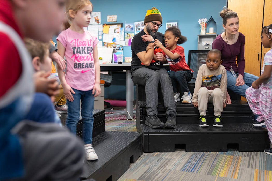 Motion City Soundtrack frontman Justin Pierre lets Gabriel Graham check out his watch before music class at Aquila Elementary School in St. Louis Park.