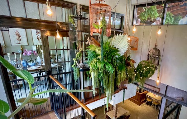 Between the lower and upper levels is a private dining area; the staircase is filled with lush greenery.