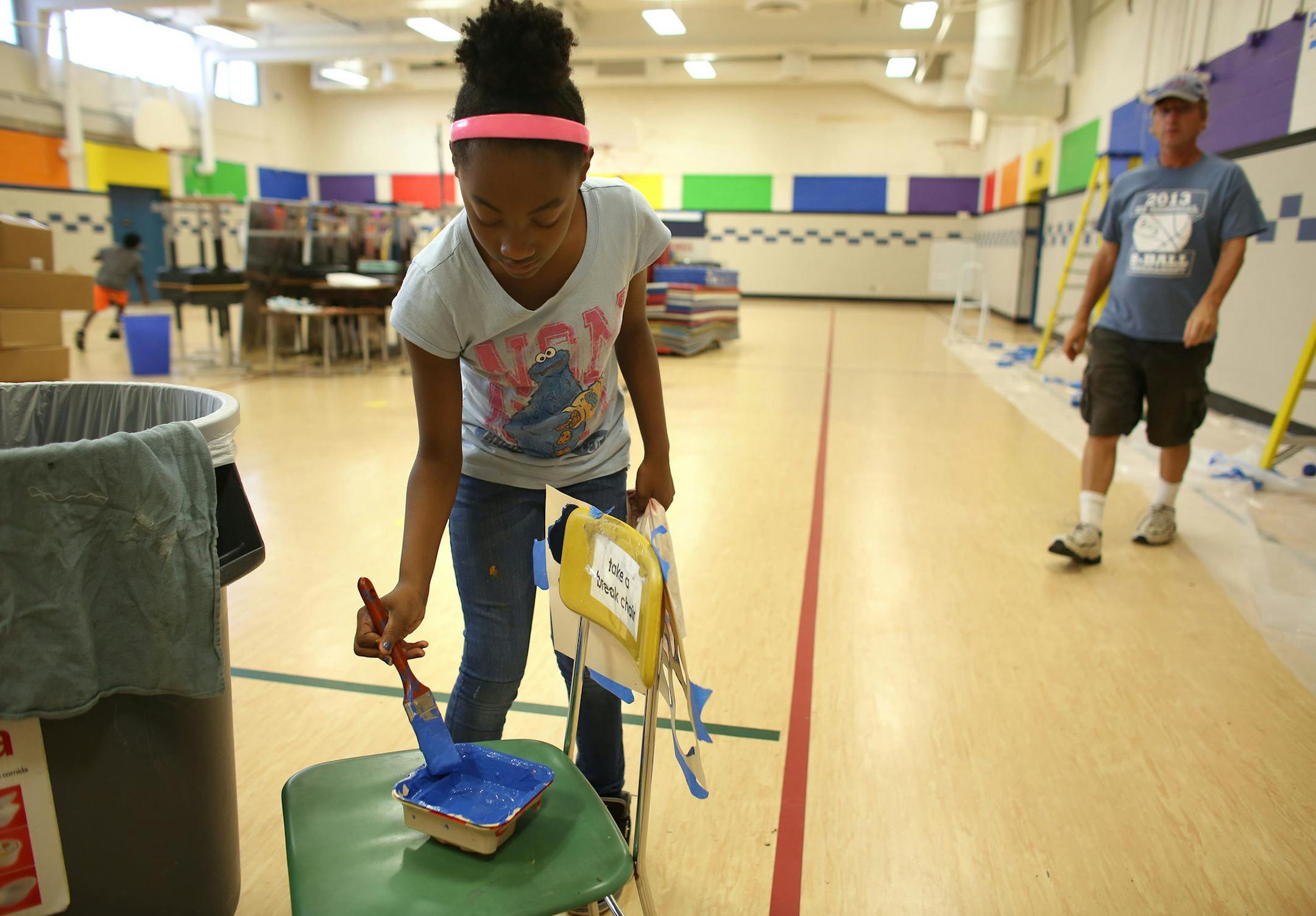 Jamiah Ward, 10, who will be a fifth grader this year, got more paint on her bush to fill in a stencil paw print that adorned the walls in the gym. ] (KYNDELL HARKNESS/STAR TRIBUNE) kyndell.harkness@startribune.com During a day of "beautification" at Northport Elementary School in Brooklyn Park, Min., Tuesday, August, 19, 2014.