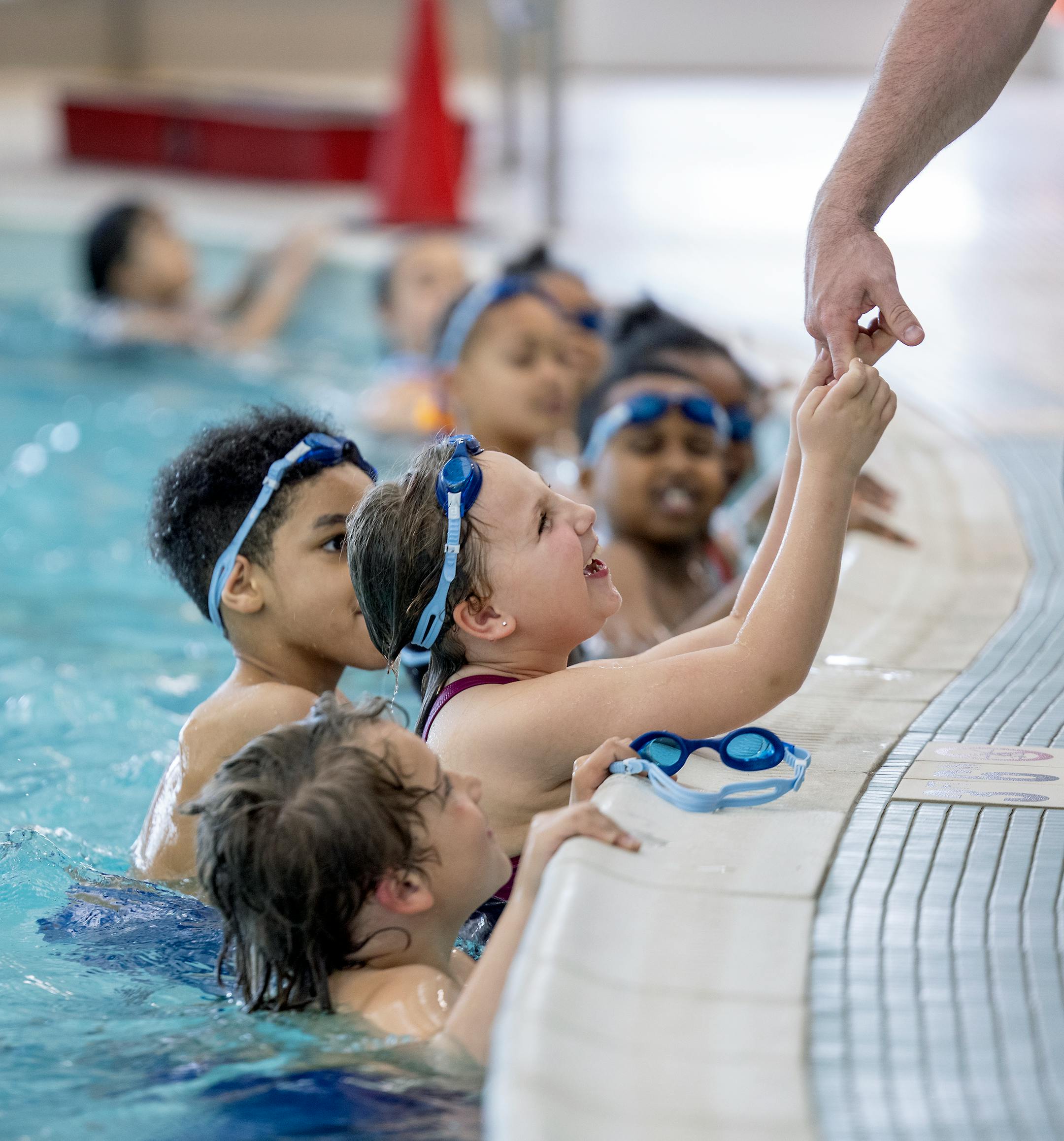 A Madison Elementary second-grader gets a little help from a teacher as she and her class learn how to exit the pool.