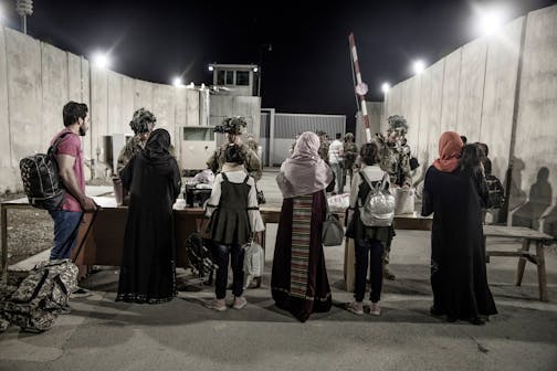 Above, in this image provided by the U.S. Marine Corps, soldiers with the 82nd Airborne Division check evacuees waiting to leave Afghanistan in 2021.
