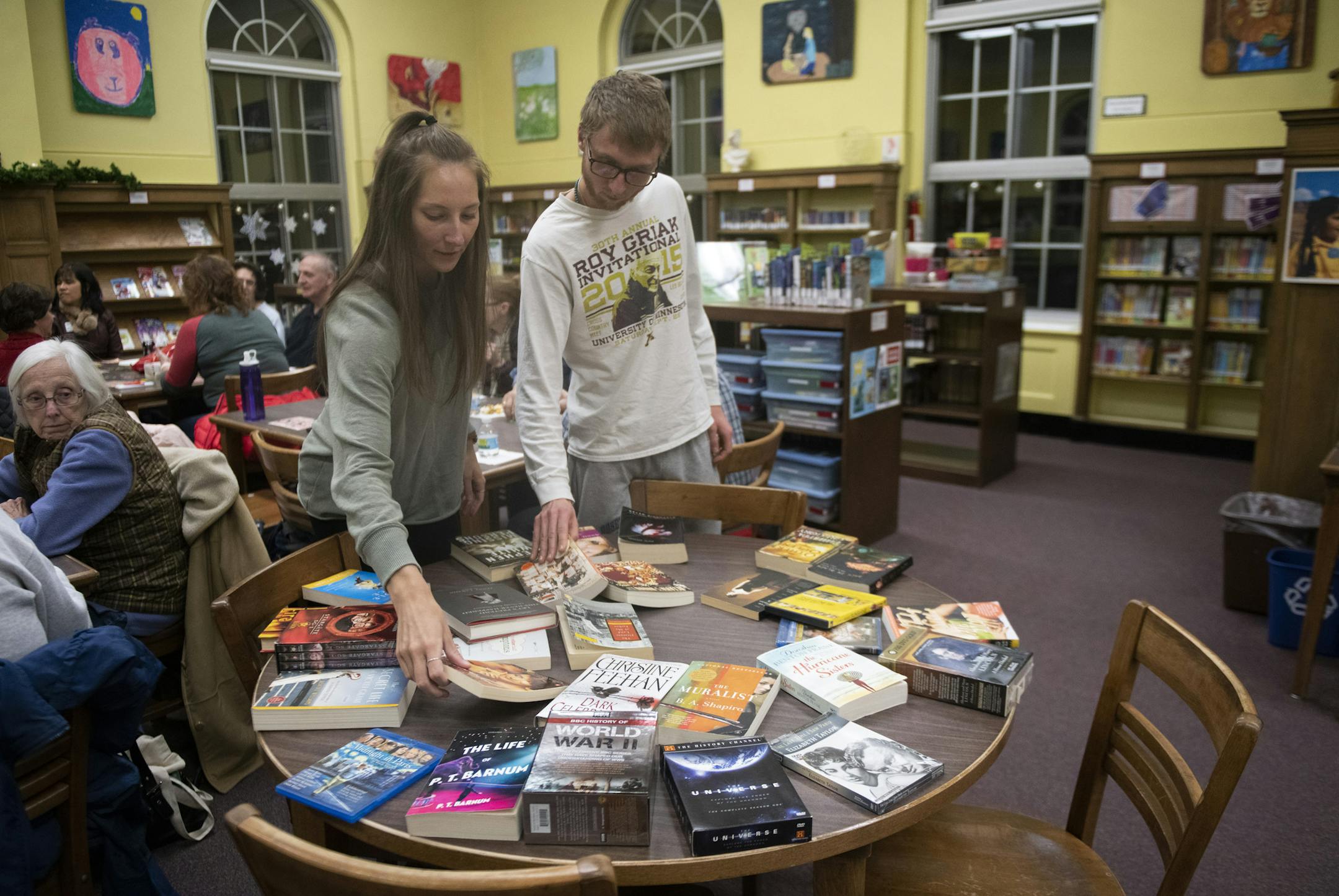 Annie McIntyre and Trevor Capra chose prizes after winning bingo. ] COURTNEY DEUTZ &#x2022; courtney.deutz@startribune.com on Thursday, February 21, 2019 at the South St. Paul Public Library. "Winter Reads Book Bingo" allowed players to win books and DVD's.