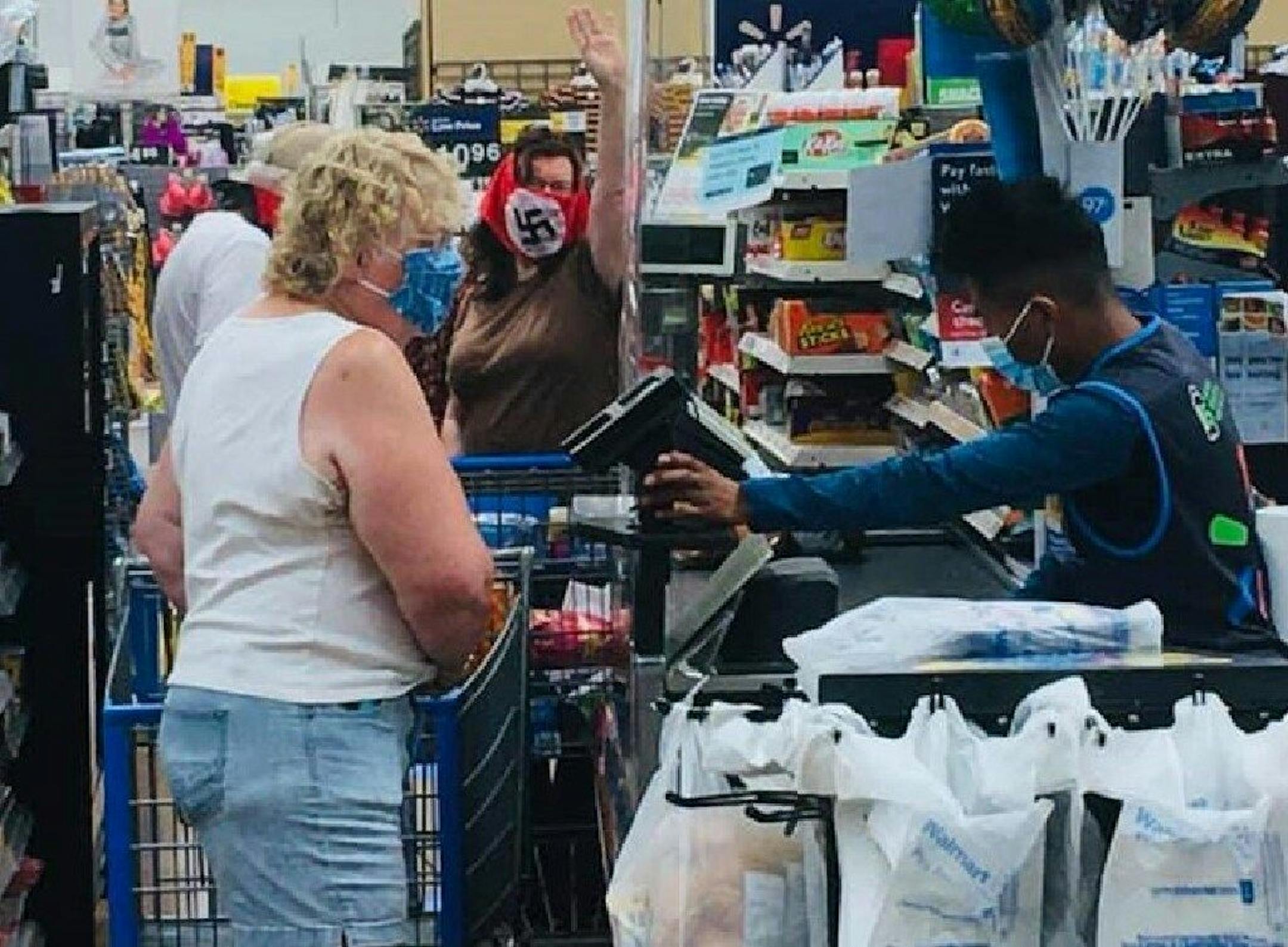 A couple wrapped in crude swastika masks shout and gesture defiantly from the back of the checkout line at a Wal-Mart in Marshall, Minn., on Saturday. Photo provided by Raphaela Mueller: