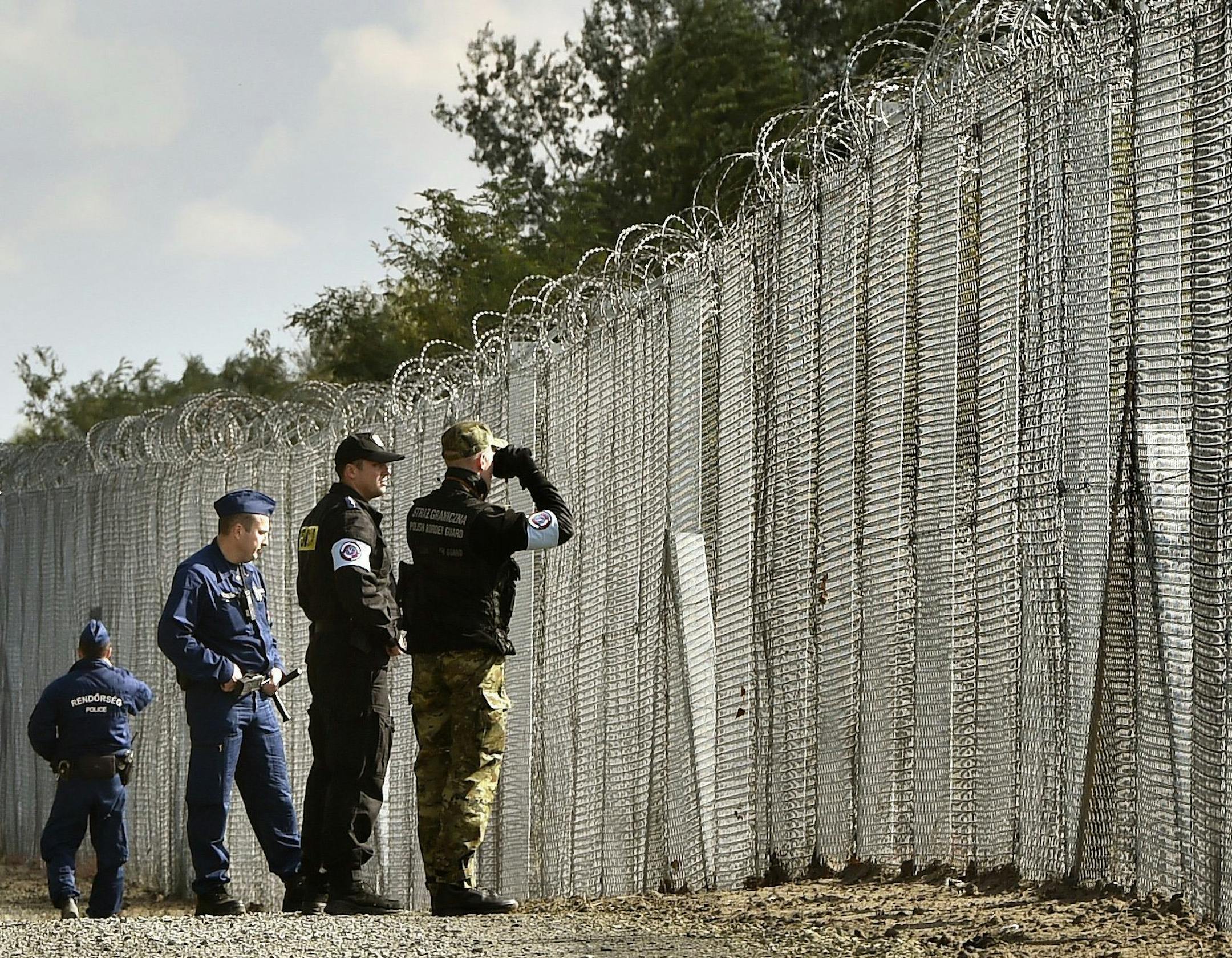 FILE - In this Oct. 13, 2016 file picture a police officer, second right, and border guard, right, of Poland patrol with Hungarian policemen along the temporary border fence on the Hungarian-Serbian border near Roszke, 180 kms southeast of Budapest, Hungary. Hungary built fences along its southern borders with Serbia and Croatia in 2015, when thousands of migrants a day were passing through the country each day on their way to Germany and other destinations in western Europe. (Zoltan Mathe/MTI v