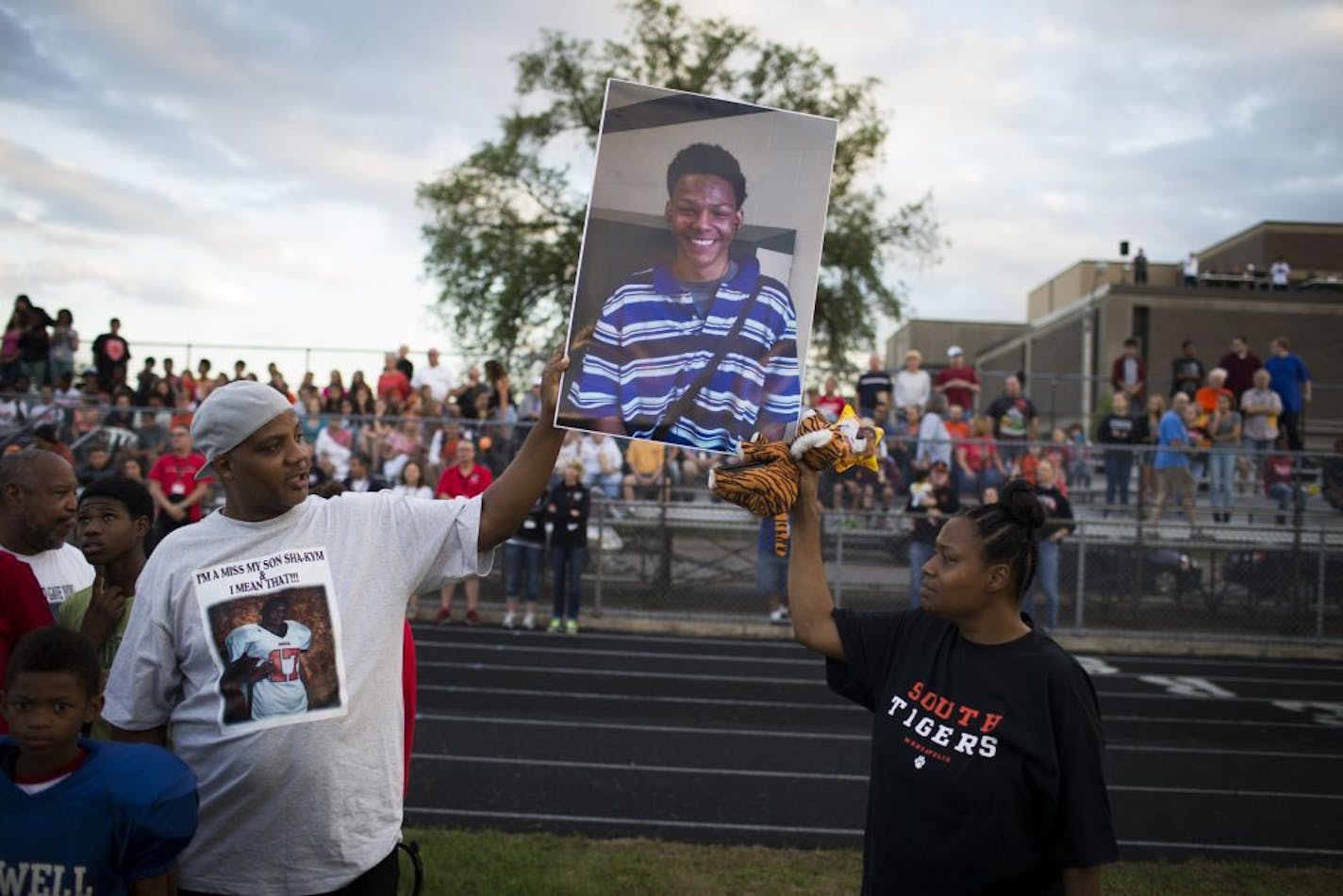 Sha-kym Adam's parents Sharrod Rowe and Kimberly Adams held up a picture of their son during a memorial time for him at the first football game of the season at South High School in Minneapolis, Minn. August 27, 2014. Adams was a football player and died earlier this month in a drowning accident.