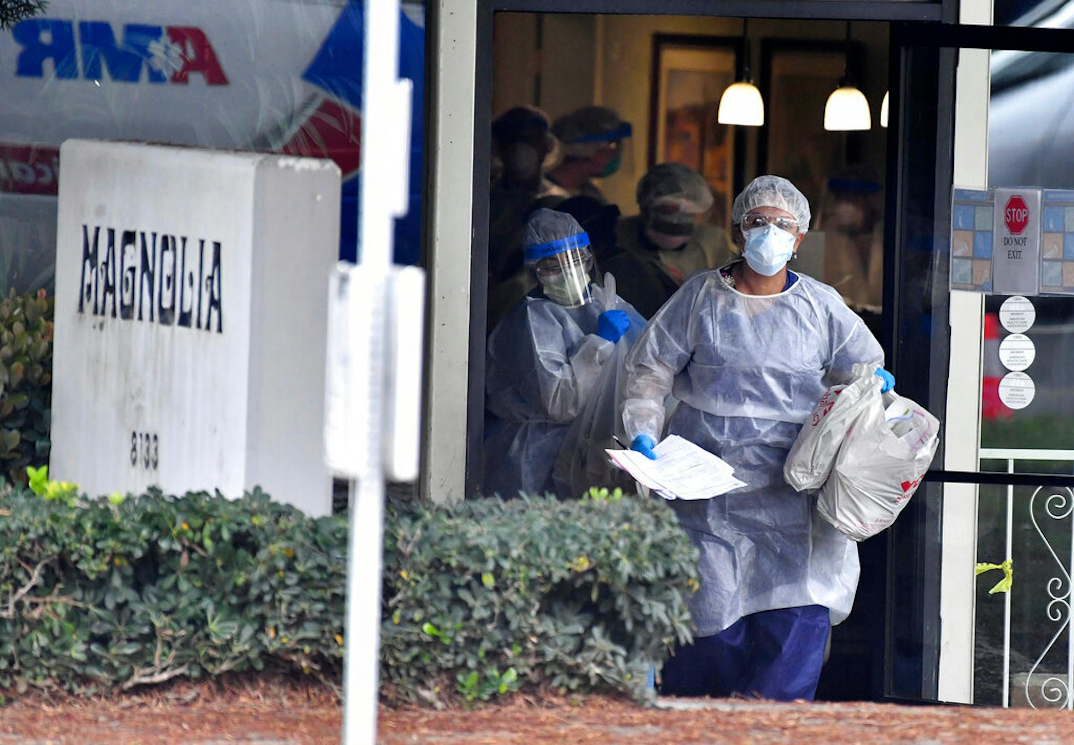 Health care workers carry personal belongings of a patient who is evacuated to a waiting ambulance in April at the Magnolia Rehabilitation and Nursing Center in Riverside, Calif.