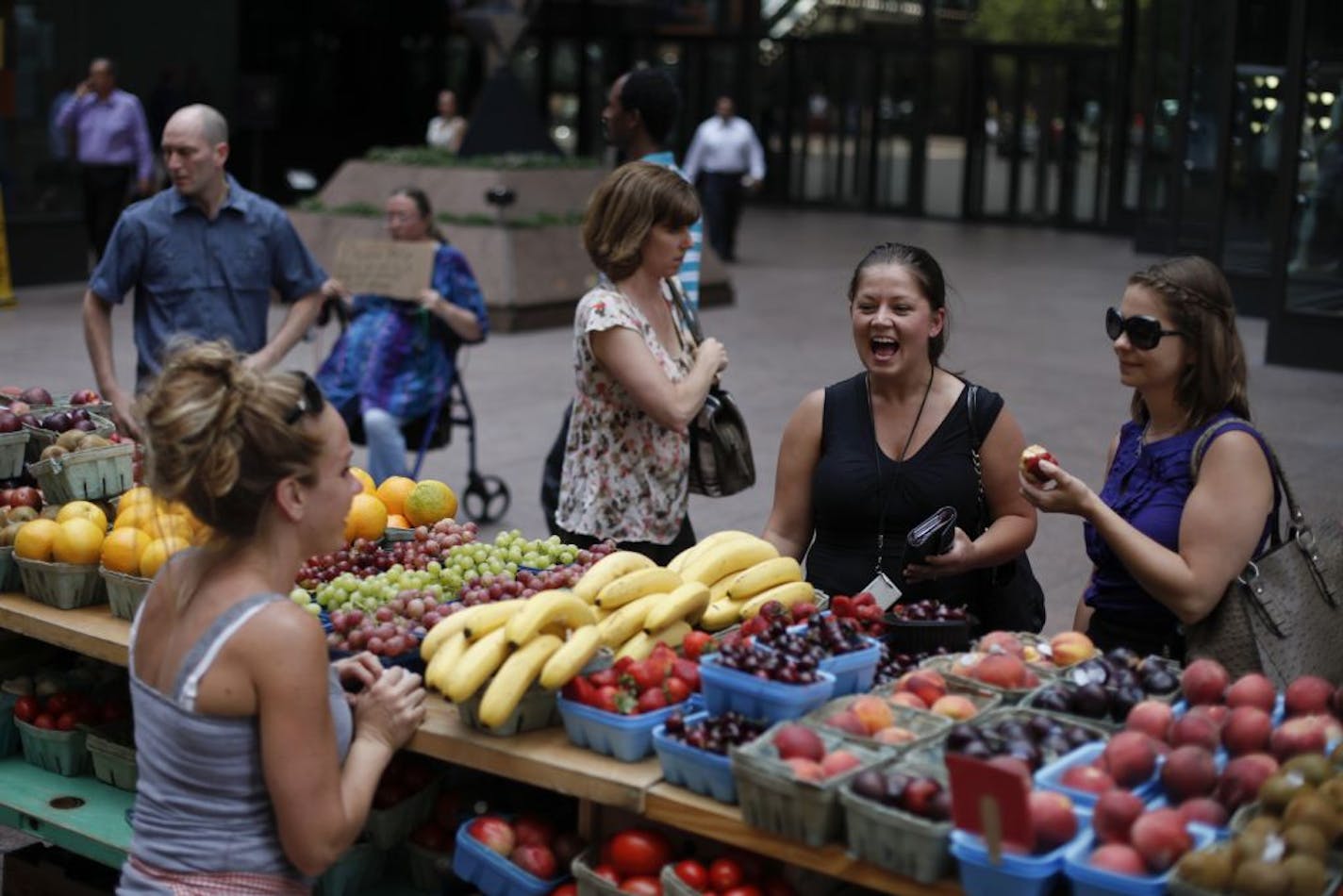 Mandy Kopnick, center, and Meredith Werderitch were first-timers at the Nicollet Mall farmers market in Minneapolis on June 5, checking out the fruit at Patnodes Produce stand. Besides getting outdoors at lunchtime, "we also wanted to support the locals," said Werderitch.