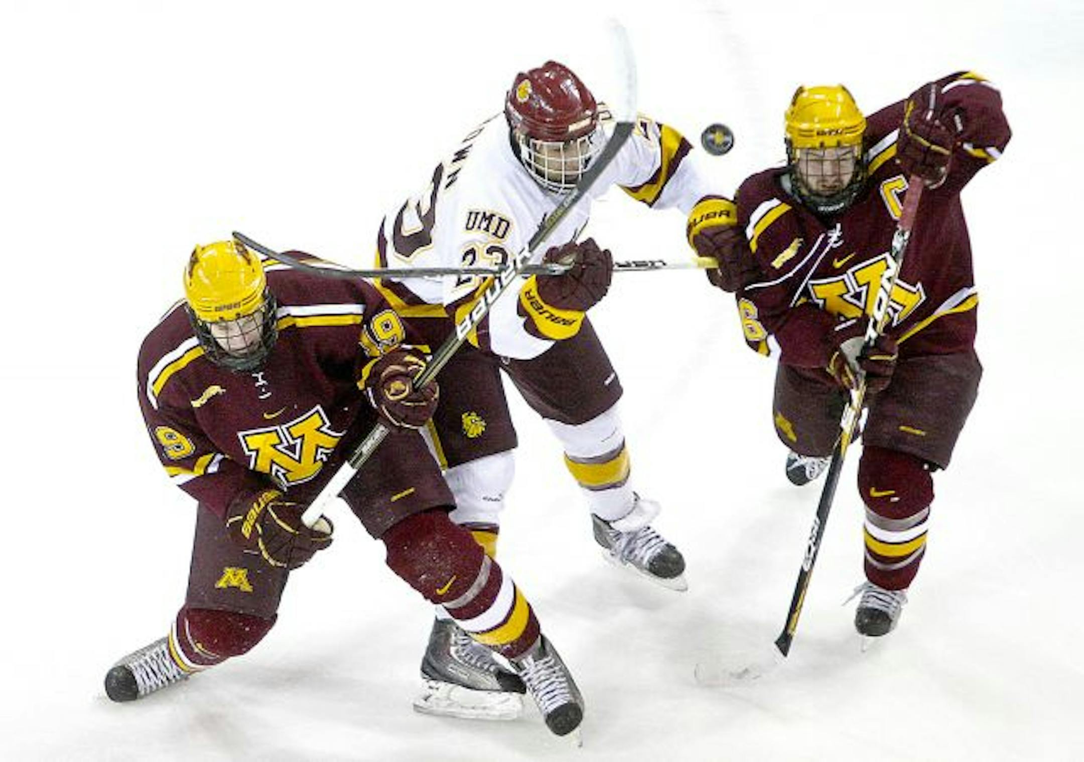 Minnesota Duluth's J.T. Brown, center, fights for the puck between Minnesota's Erik Haula (19) and Jay Barriball (26) during an NCAA college hockey game on Friday, Feb. 4, 201, in Duluth, Minn.