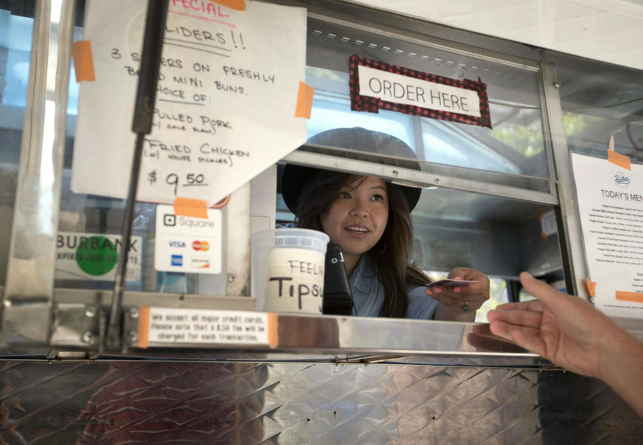 In this photo taken, July 10, 2015, food truck Peachesí Smokehouse & Southern Kitchen co-owner Diana Lamon hands a credit card back to a customer after taking an order in Burbank, Calif. The health care law, minimum wage increases and paid sick leave laws in some states and cities are increasing costs for business owners like Lamon. (AP Photo/Jae C. Hong) ORG XMIT: NYBZ401