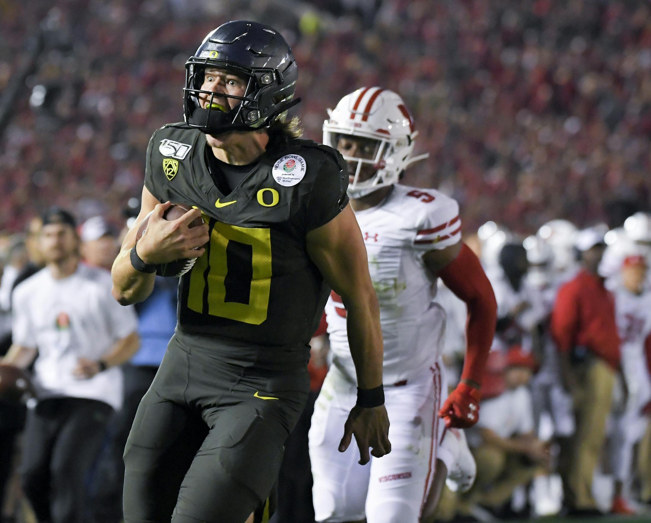 Oregon quarterback Justin Herbert runs for a touchdown past Wisconsin cornerback Rachad Wildgoose during second half of the Rose Bowl NCAA college football game Wednesday, Jan. 1, 2020, in Pasadena, Calif. (AP Photo/Mark J. Terrill)