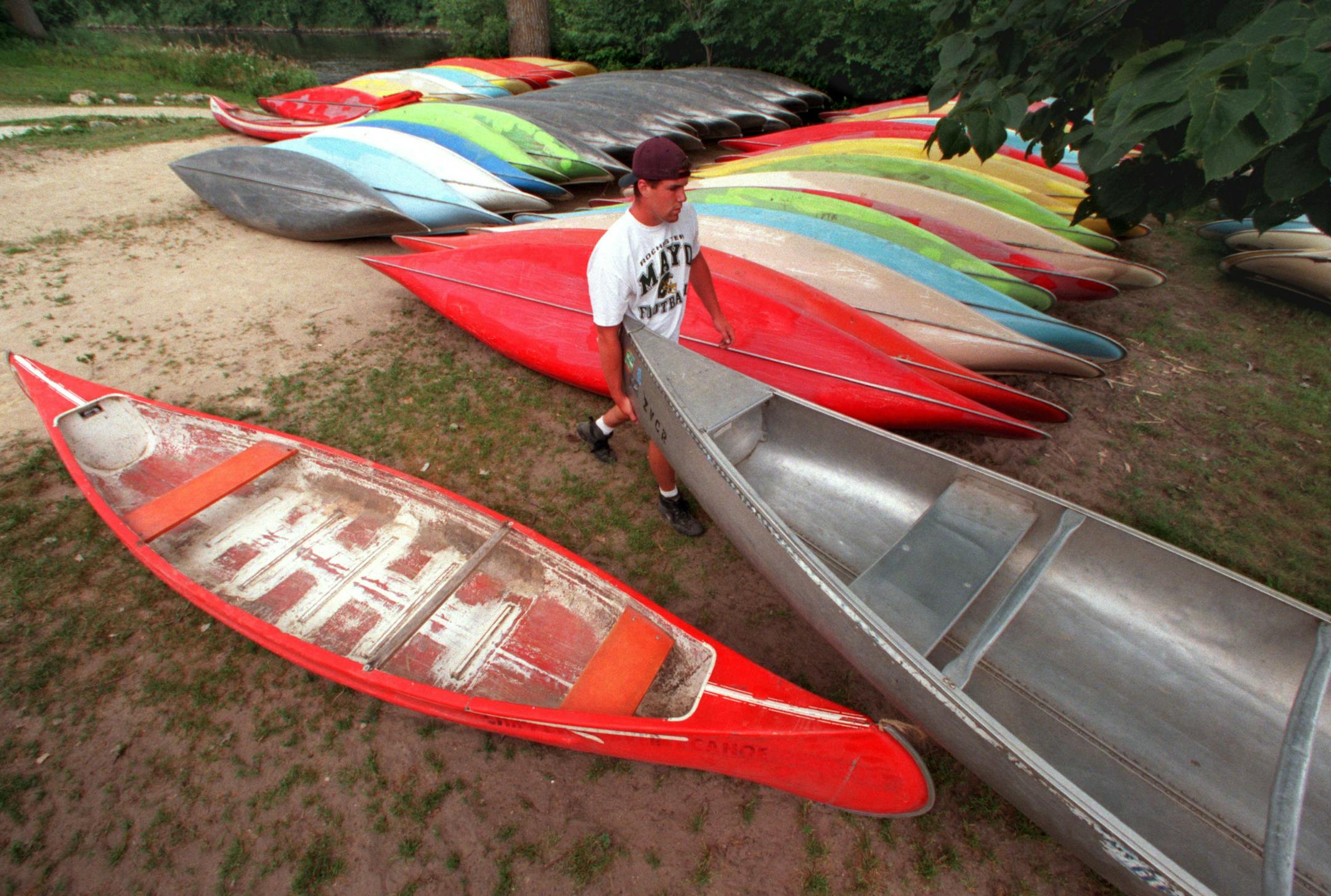 MATT GREESON, AN EMPLOYEE OF ZUMBRO VALLEY CANOE RENTAL IN ZUMBRO FALLS, HELPS A PADDLER CARRY ONE OF THE SEVERAL HUNDRED CANOES AVAILABLE FOR RENT AND USE ON THE ZUMBRO RIVER.